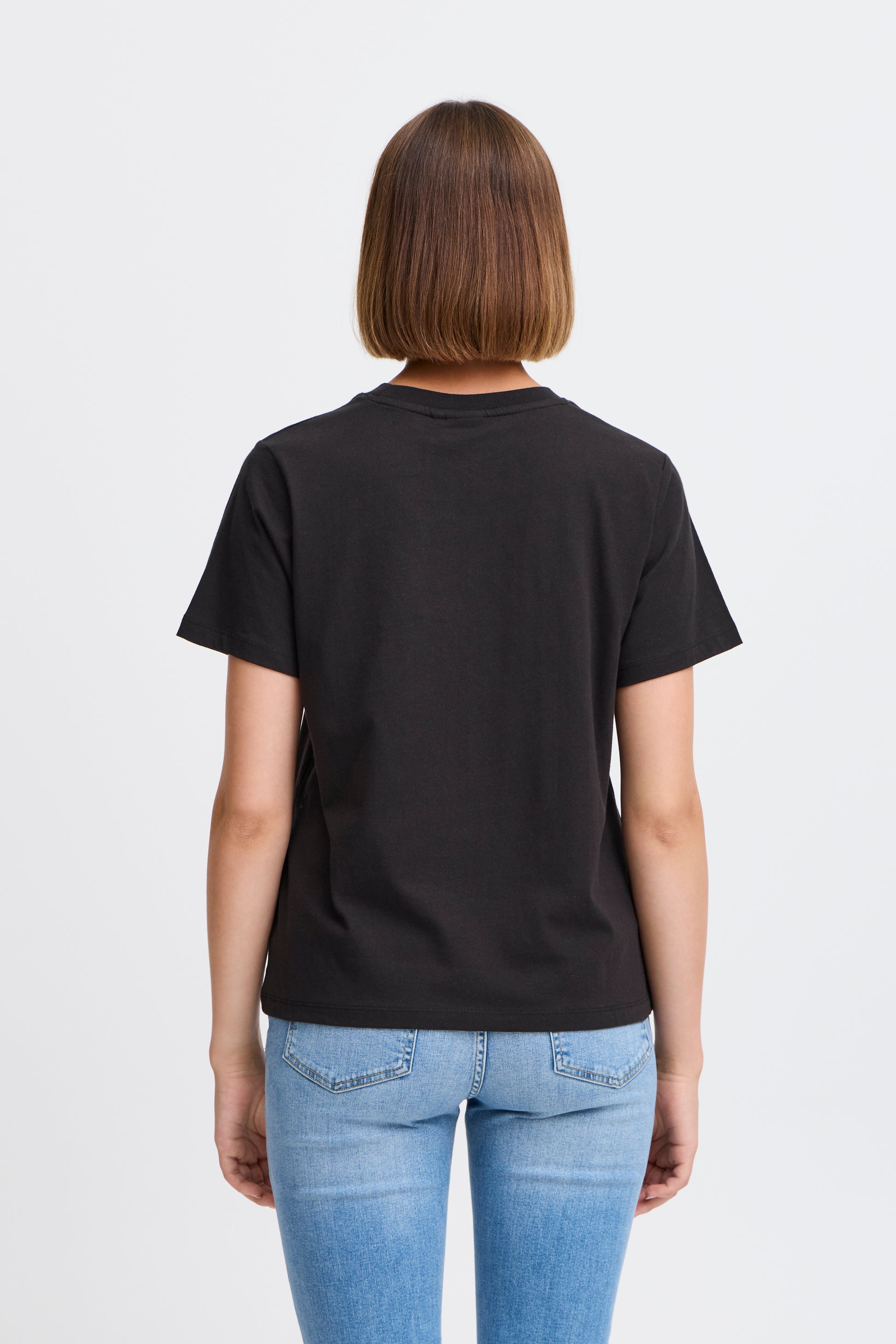 Person wearing a black t-shirt and blue jeans on a light gray background