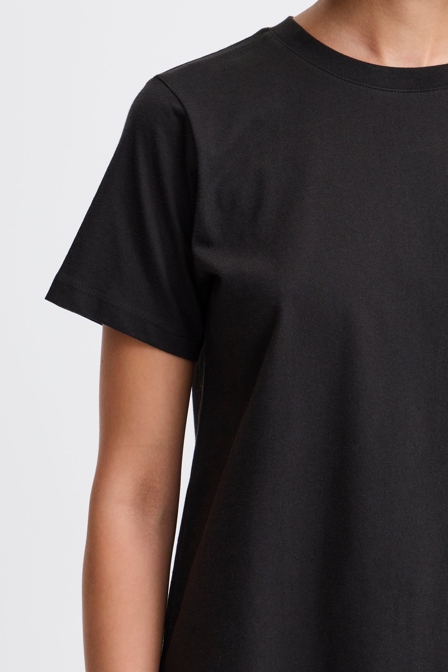 Black t-shirt worn by a person on a light gray background