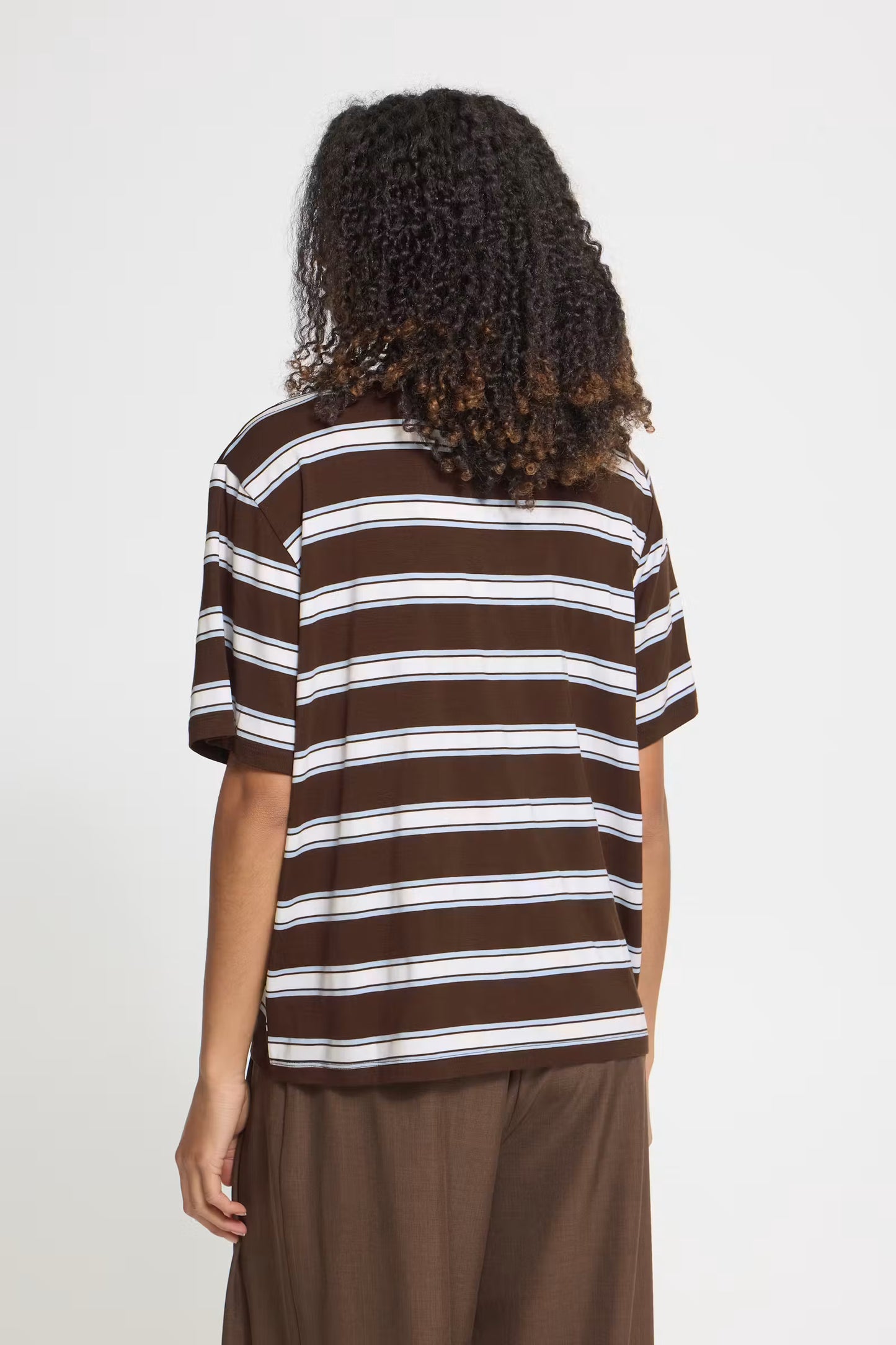 A person shown from the back wearing a brown short-sleeve striped t-shirt with white horizontal stripes and brown pants, against a plain light gray background.