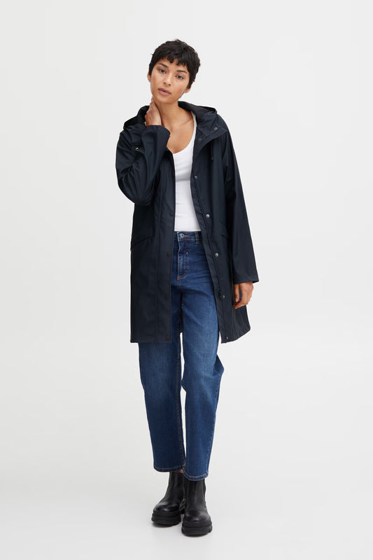 Person wearing a navy coat, white shirt, blue jeans, and black boots on a white background