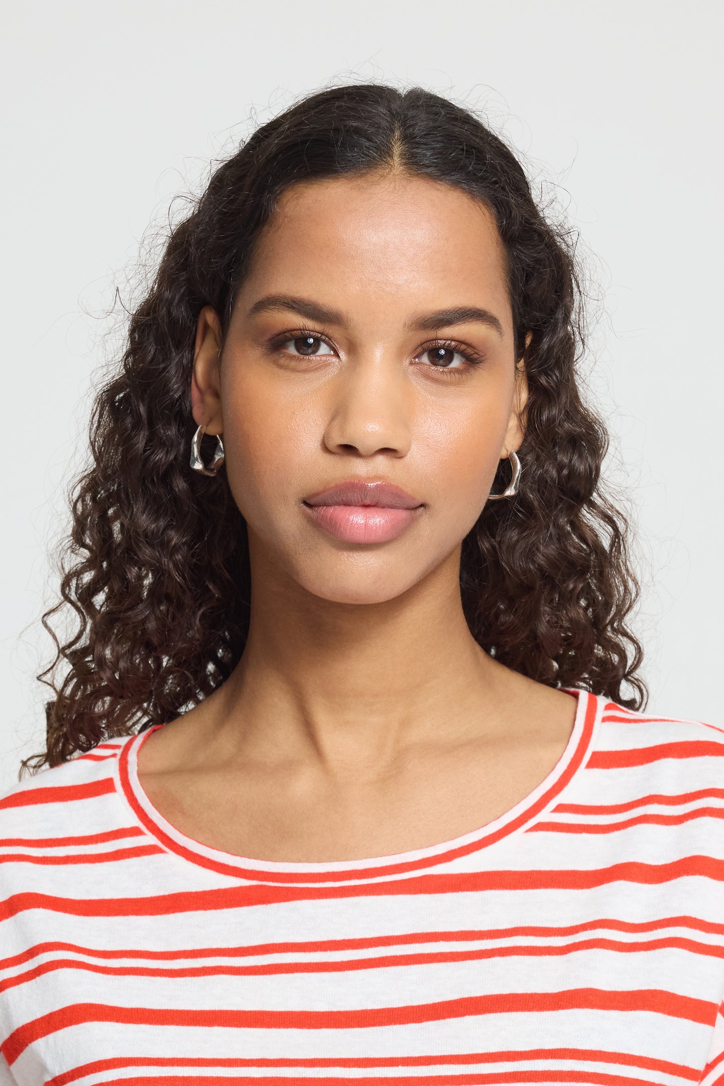 Woman wearing a red and white striped shirt against a plain background
