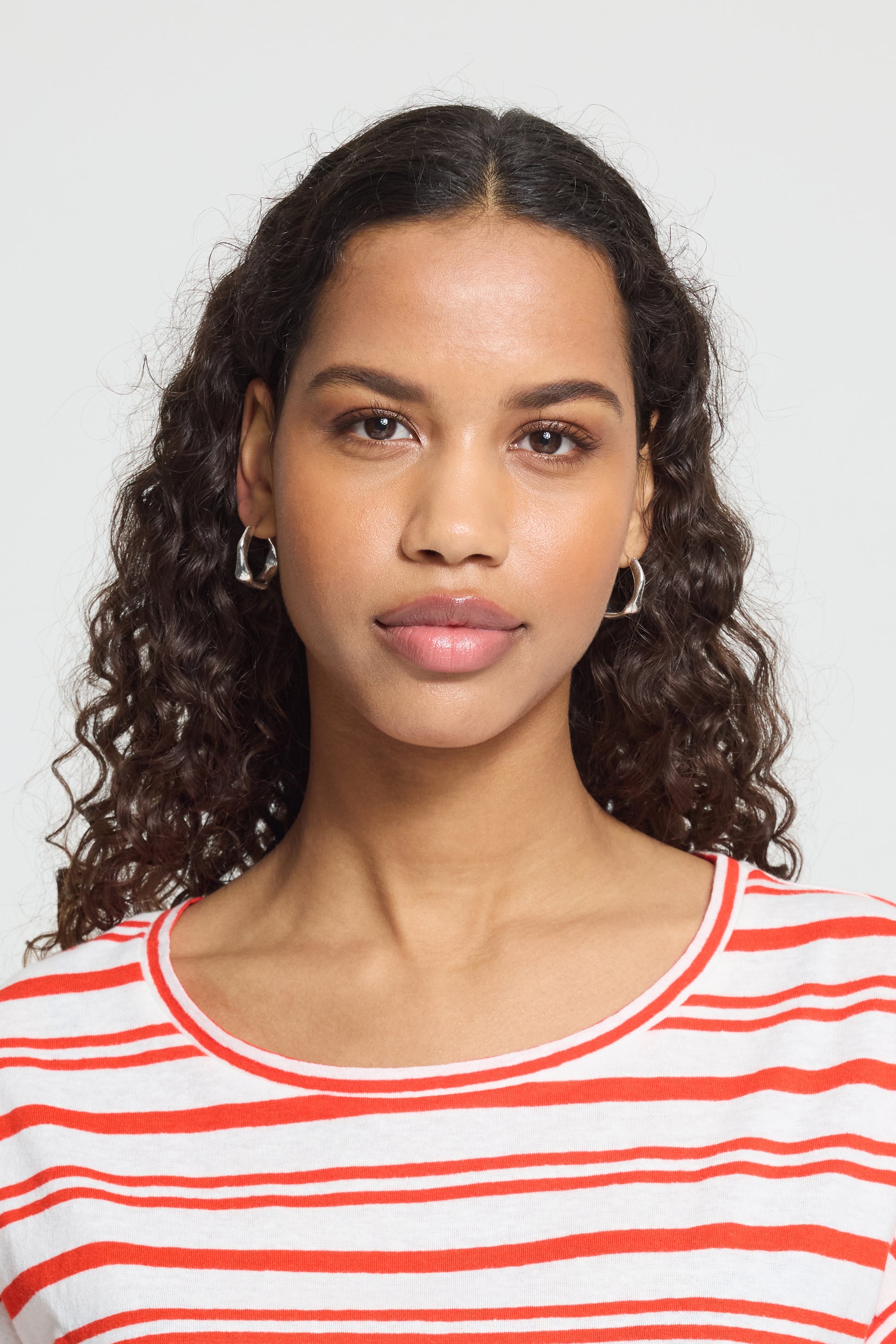 Woman wearing a red and white striped shirt against a plain background