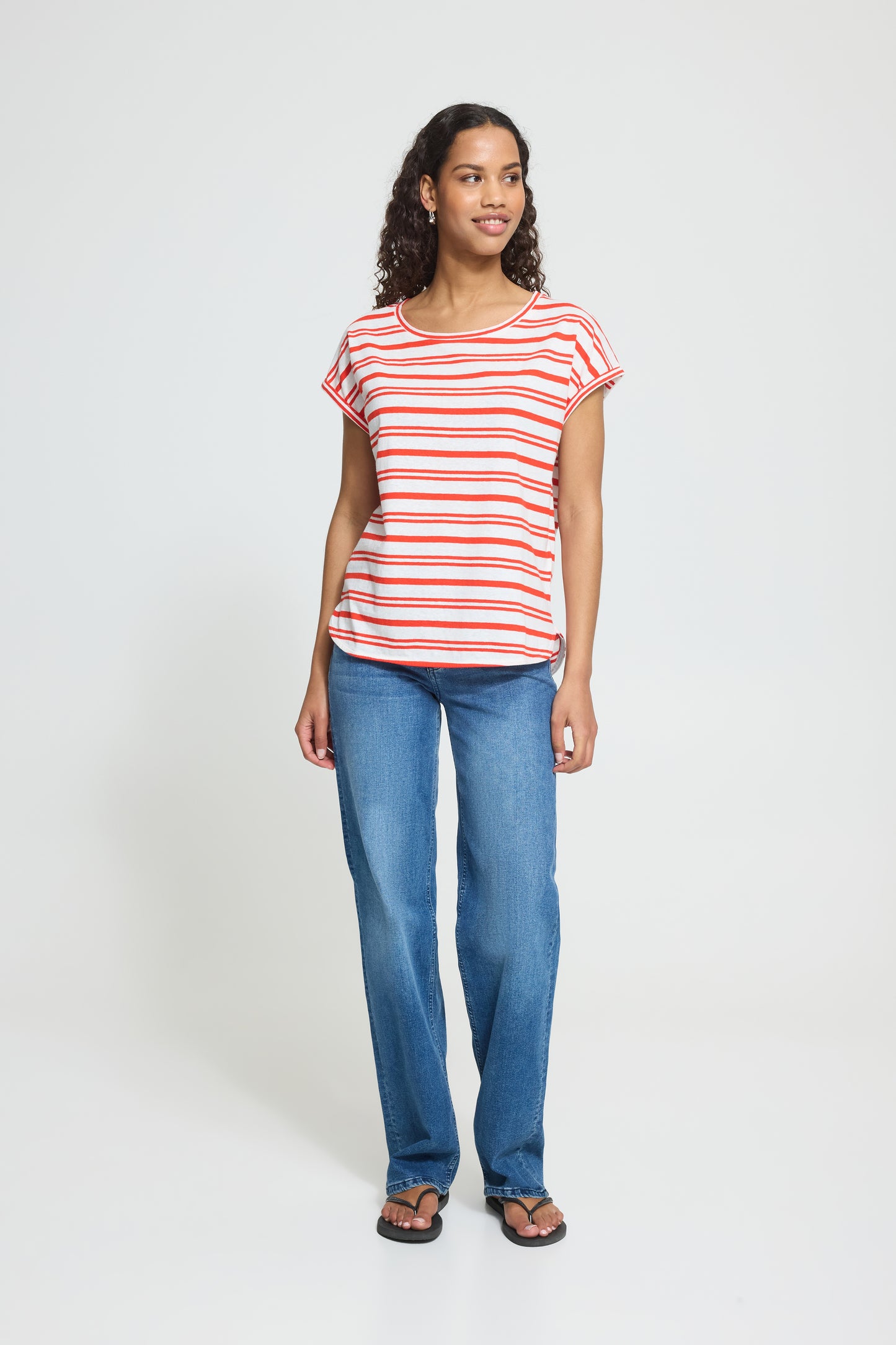 Woman wearing a red and white striped shirt and blue jeans on a white background