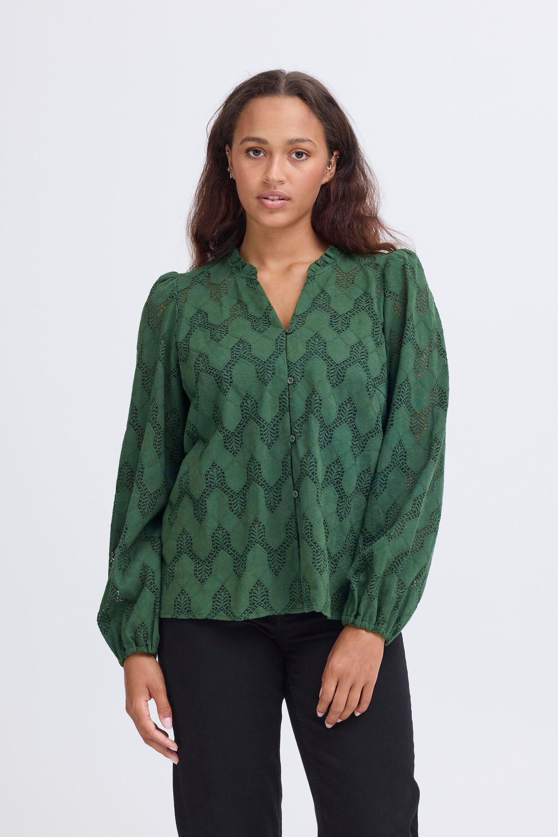Woman wearing a green patterned blouse against a white background