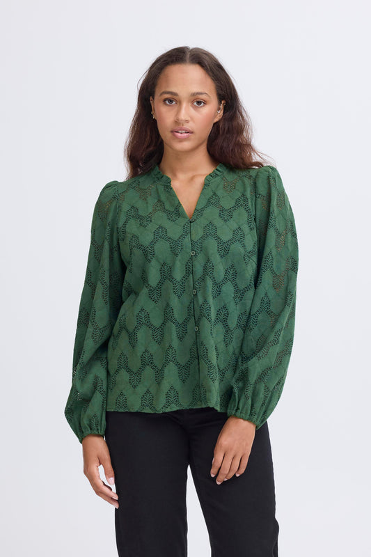 Woman wearing a green patterned blouse against a white background