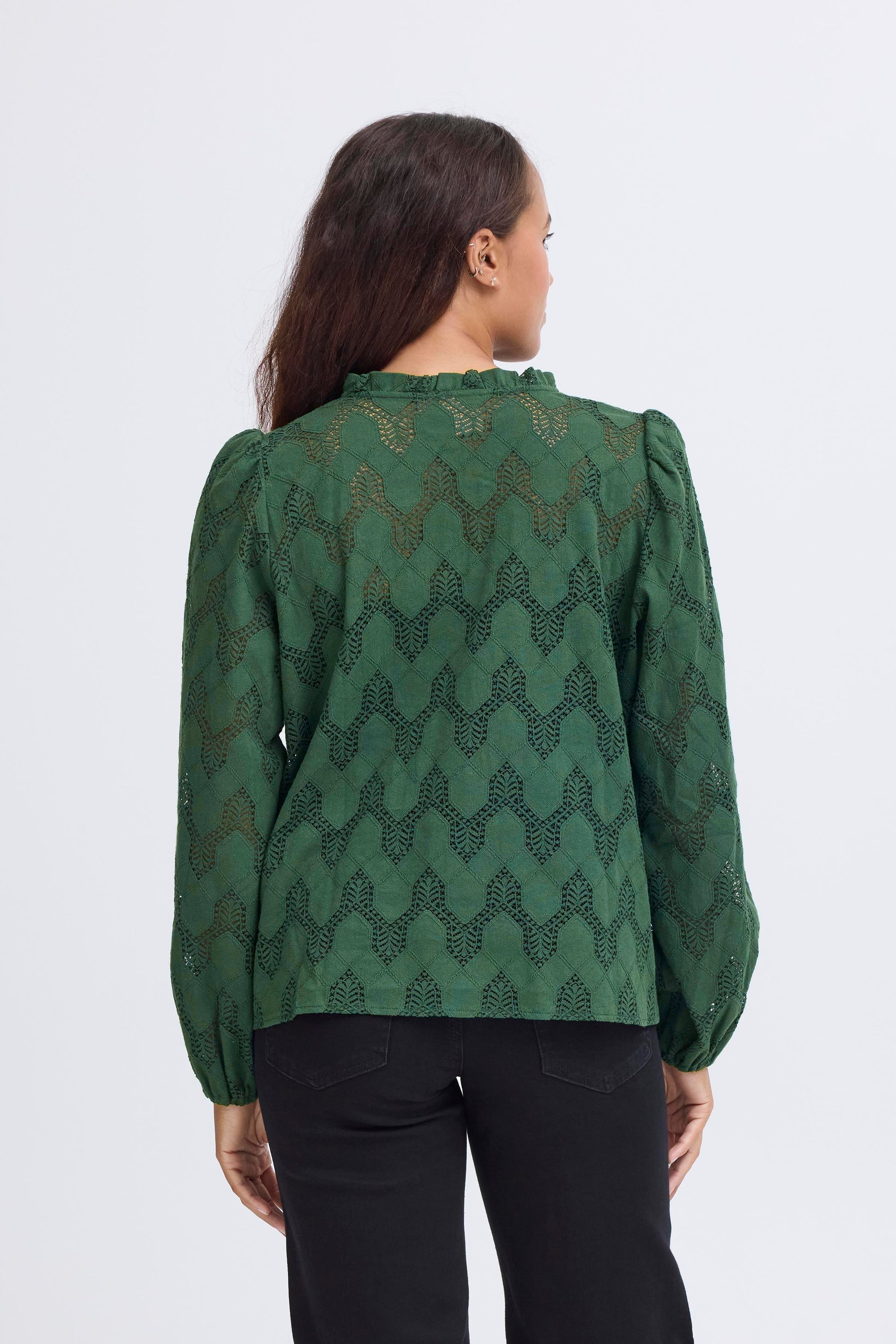 Person wearing a green patterned blouse on a white background