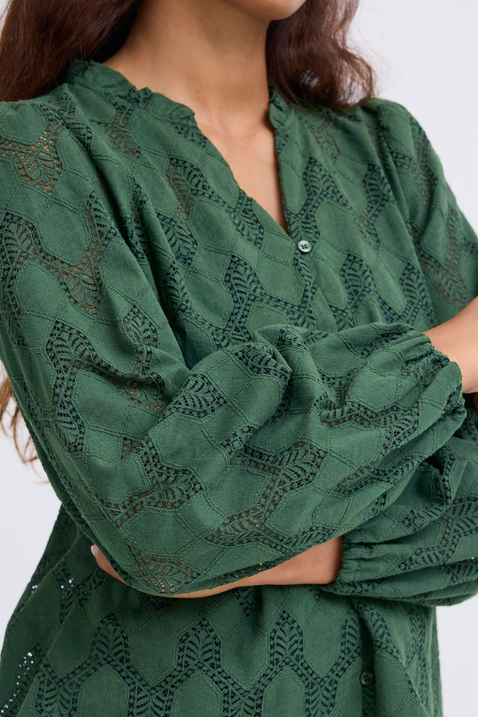Green lace top worn by a person on a white background