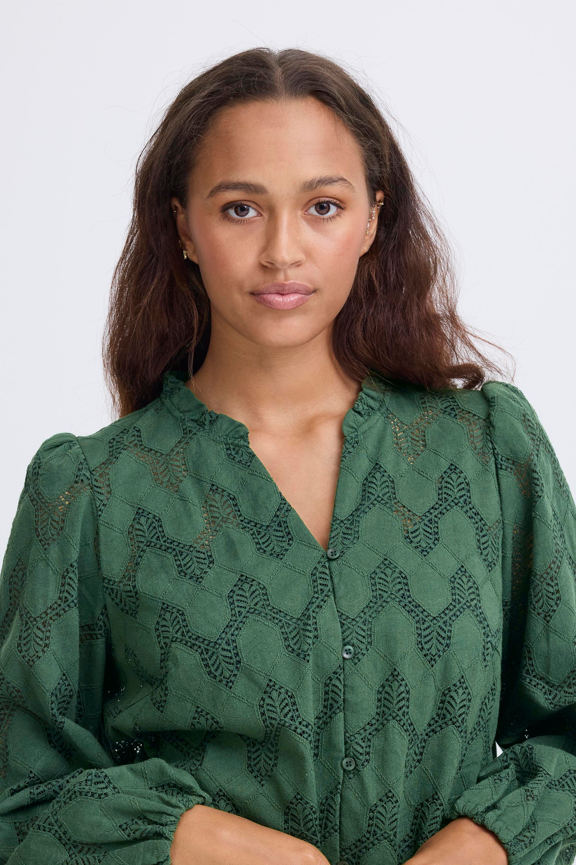 Woman wearing a green patterned blouse against a white background