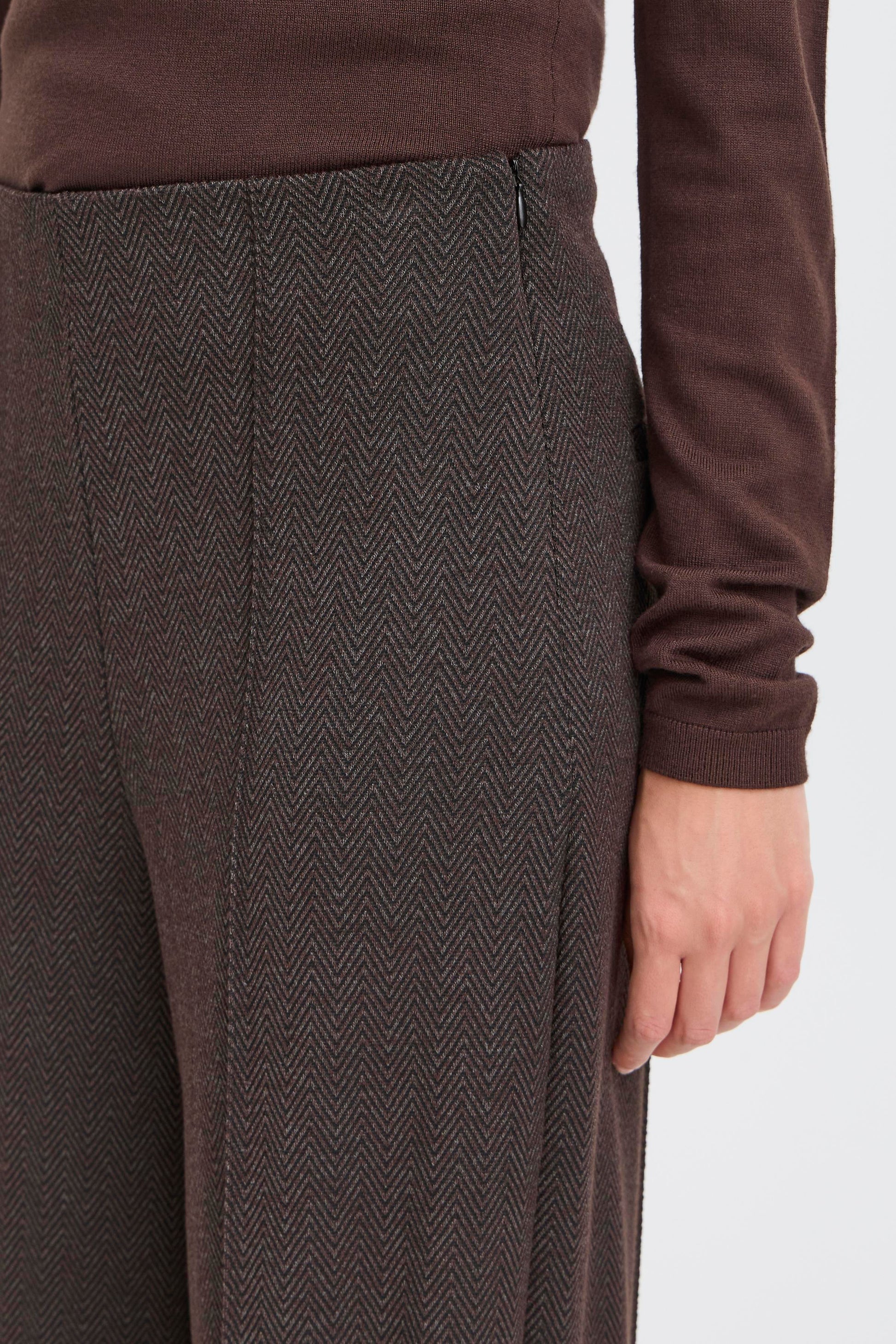 Brown sweater and herringbone-patterned pants on a white background