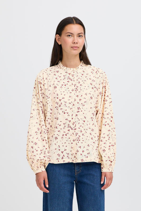 Woman wearing a floral blouse and blue jeans on a white background