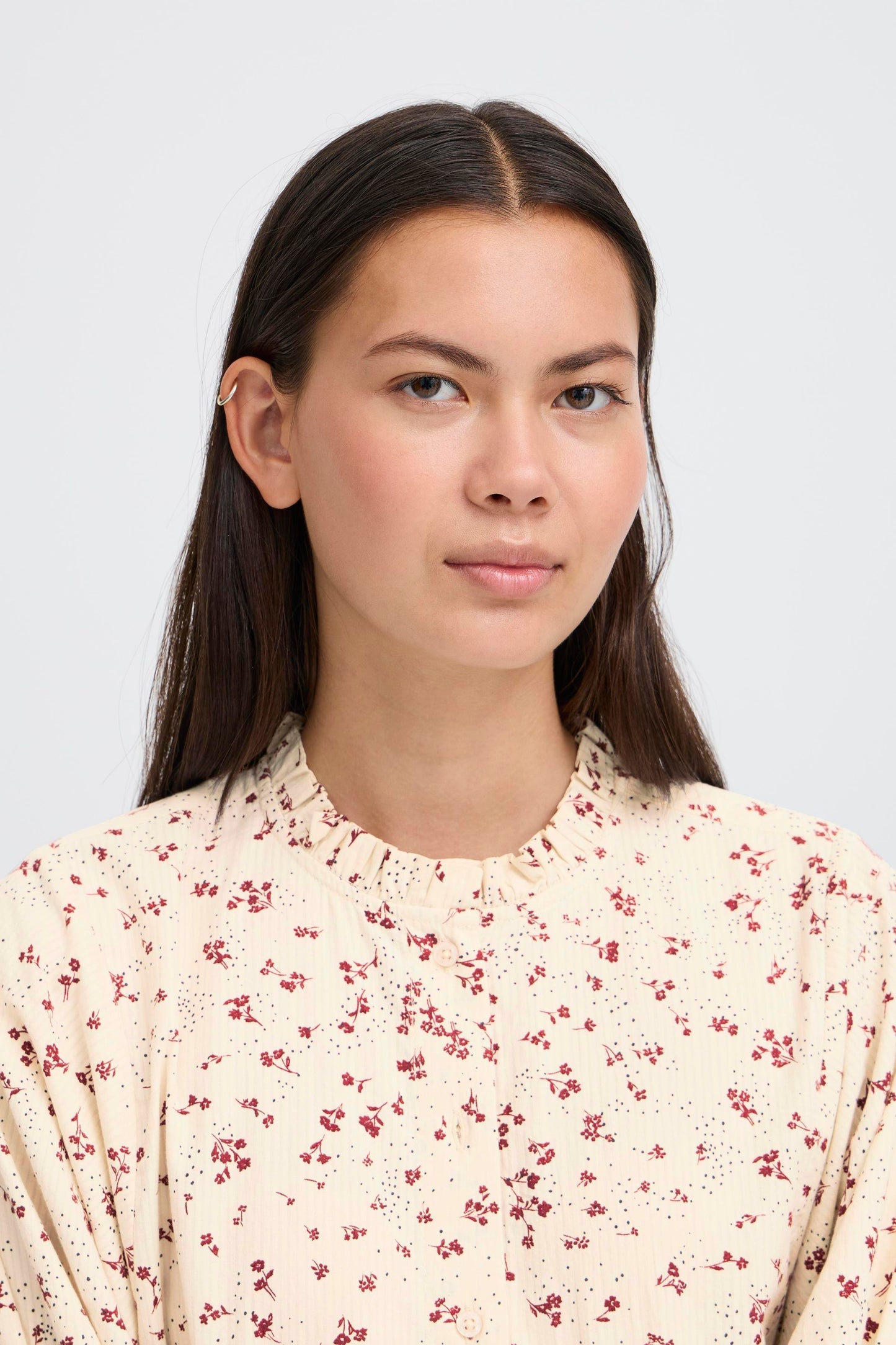 Woman wearing a floral blouse against a plain background