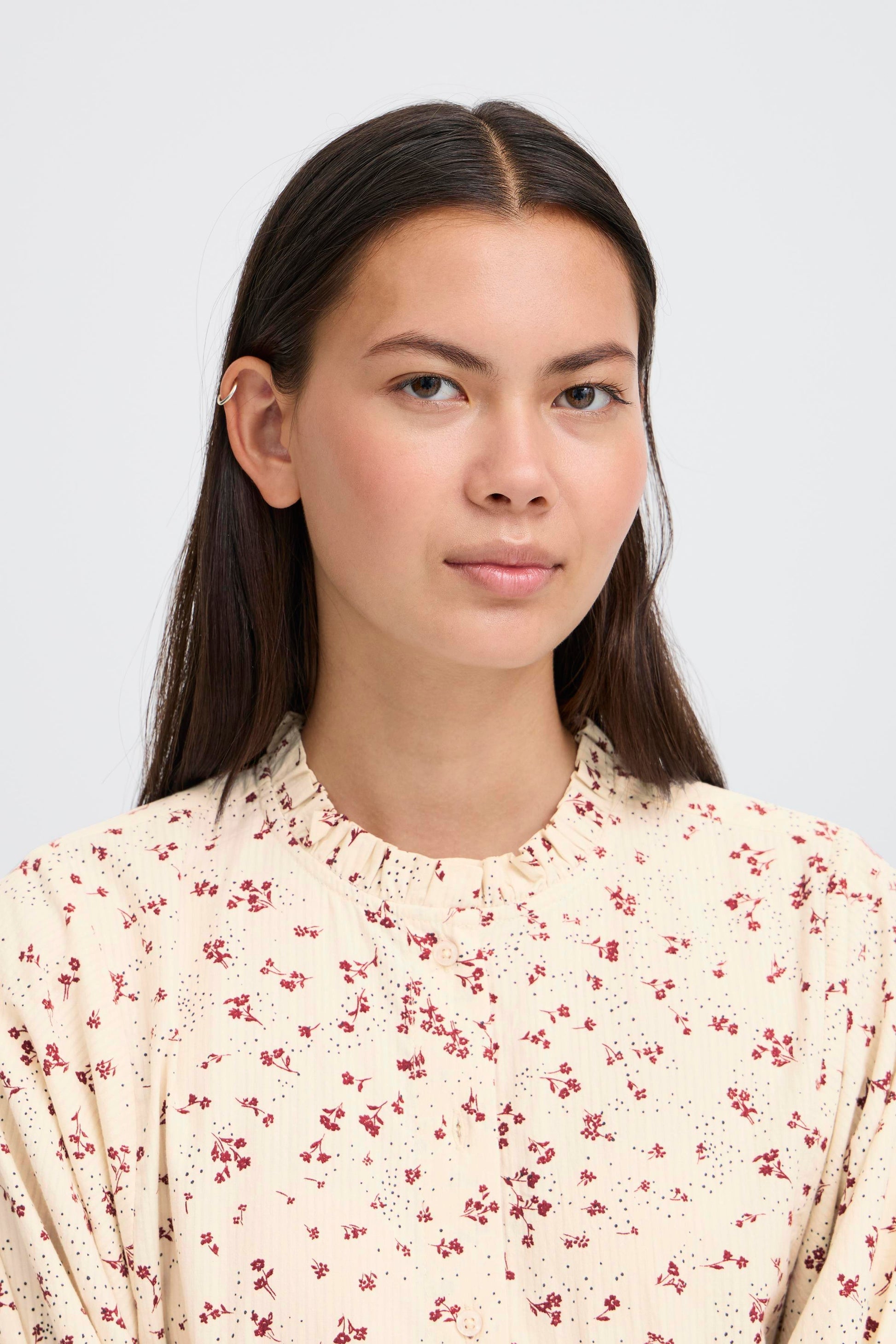 Woman wearing a floral blouse against a plain background