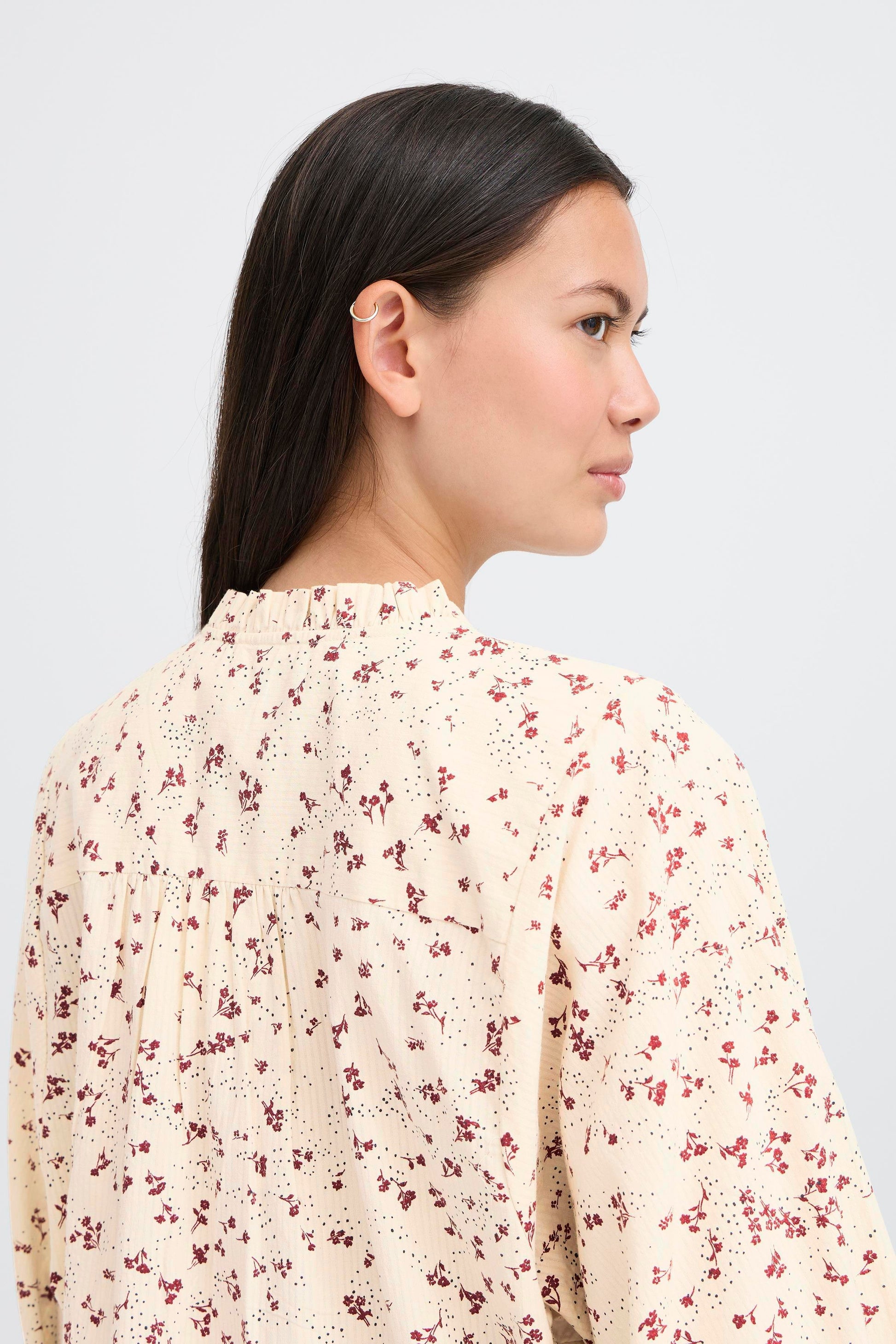 Woman wearing a floral blouse against a plain background