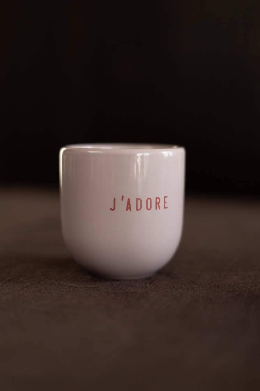 White mug with 'J'adore' text on a dark background