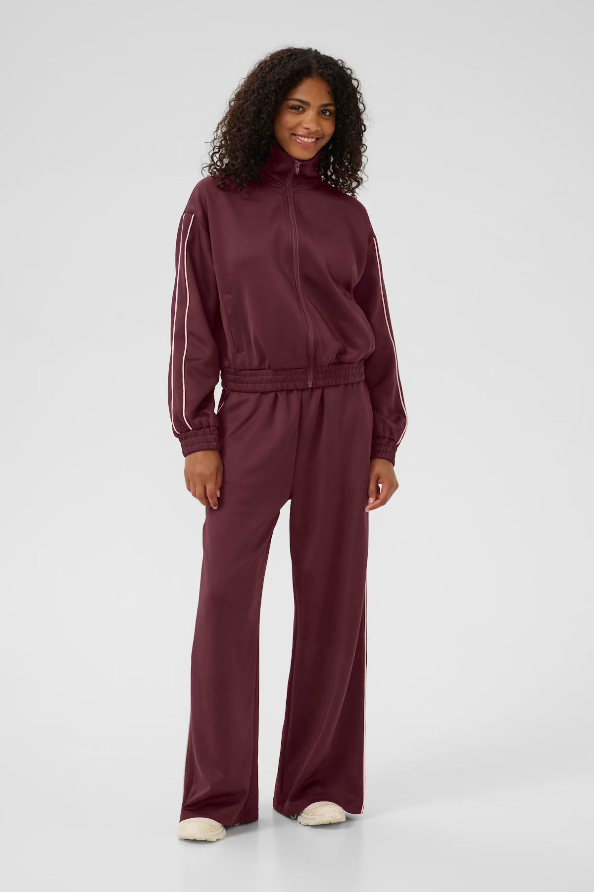 Woman wearing a burgundy tracksuit on a white background
