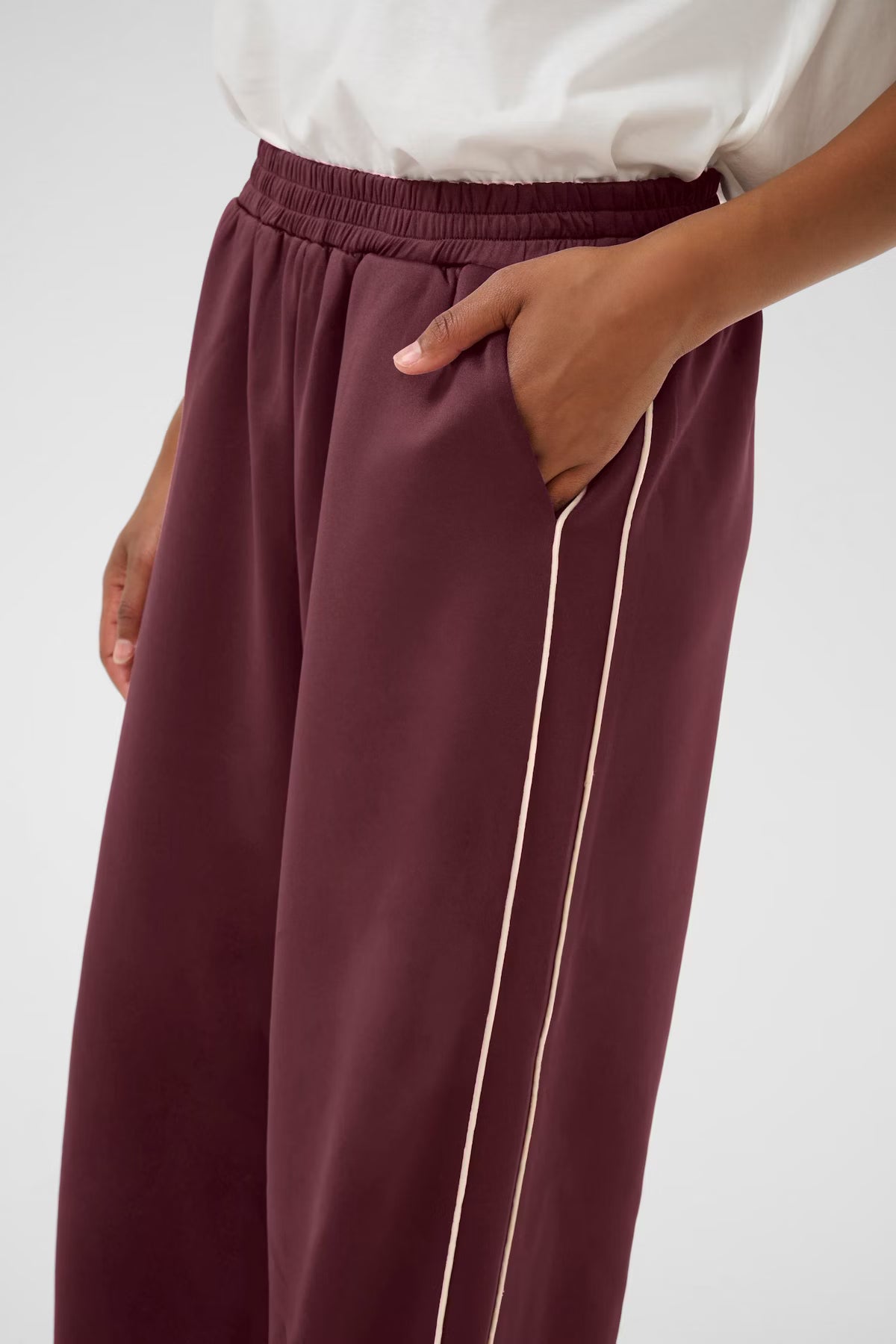 Maroon pants with a white top on a plain background