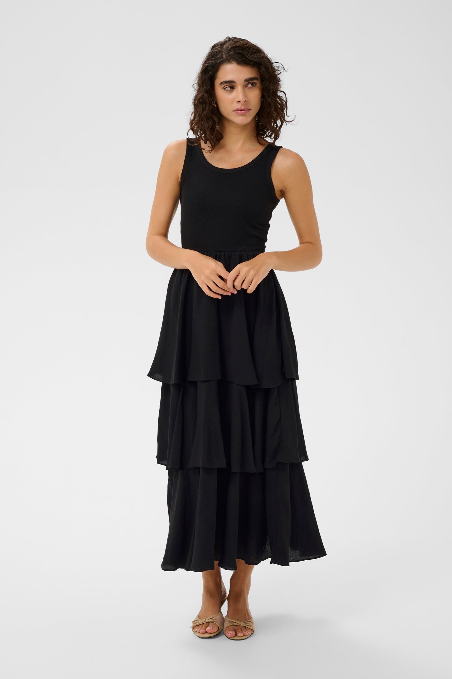 Woman wearing a black tiered dress on a white background