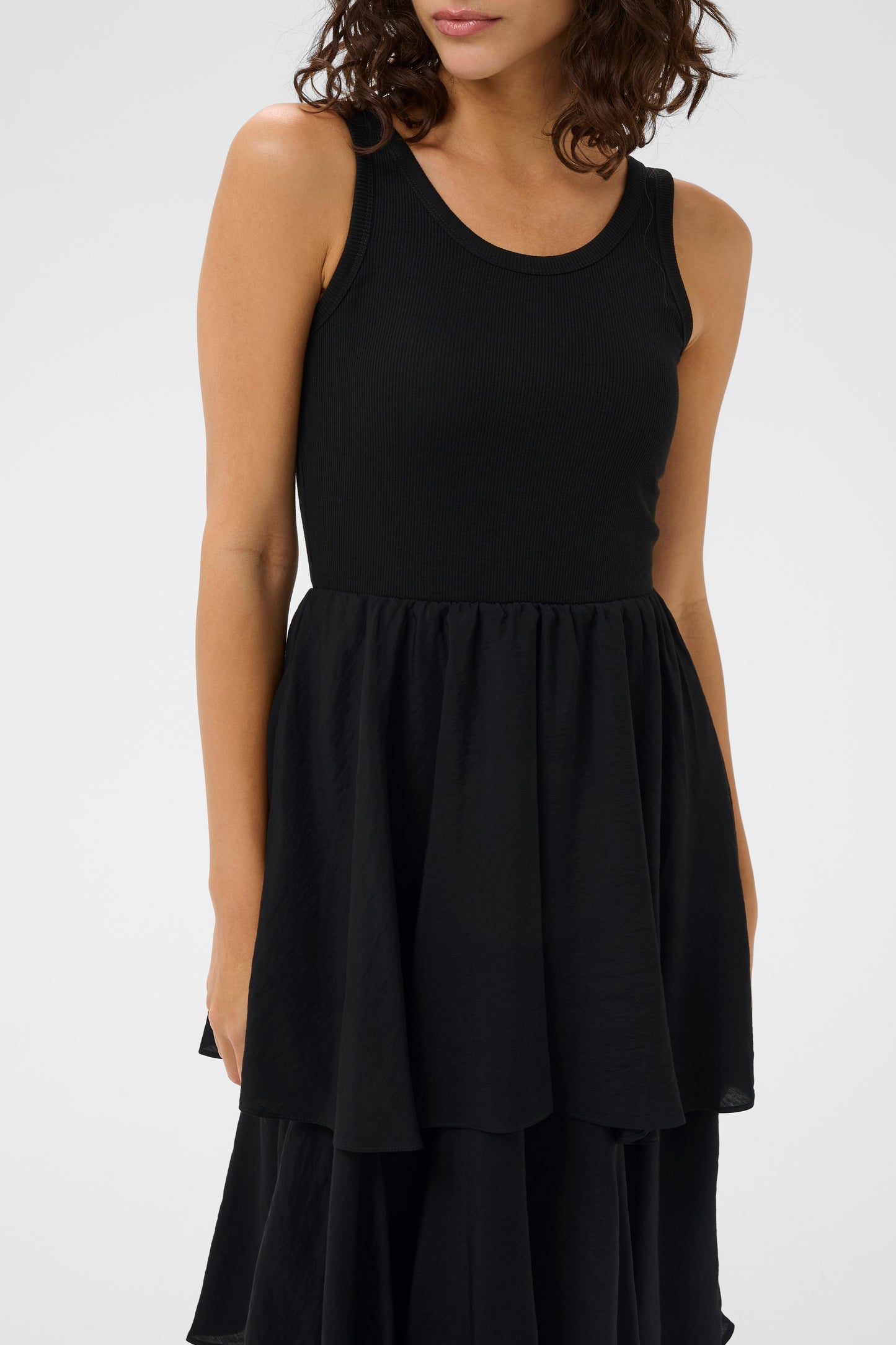 Black sleeveless dress worn by a model on a white background
