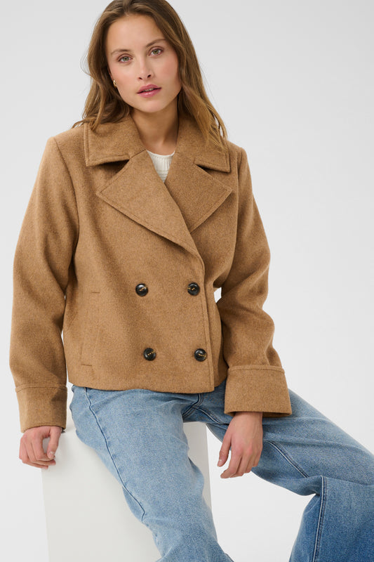 Woman wearing a brown coat and blue jeans on a white background