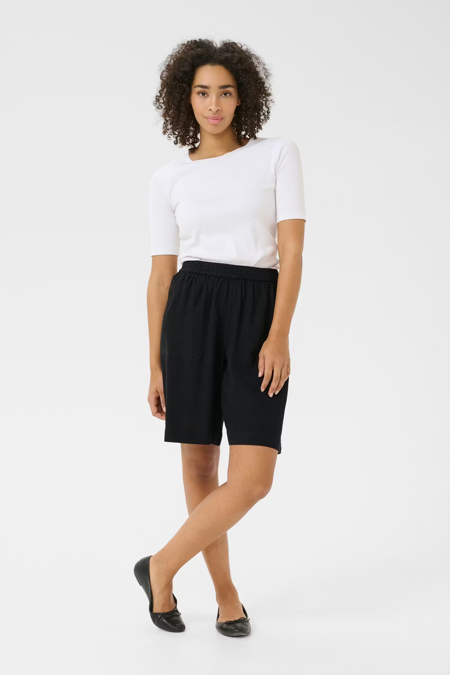 Woman wearing a white top and black shorts on a white background