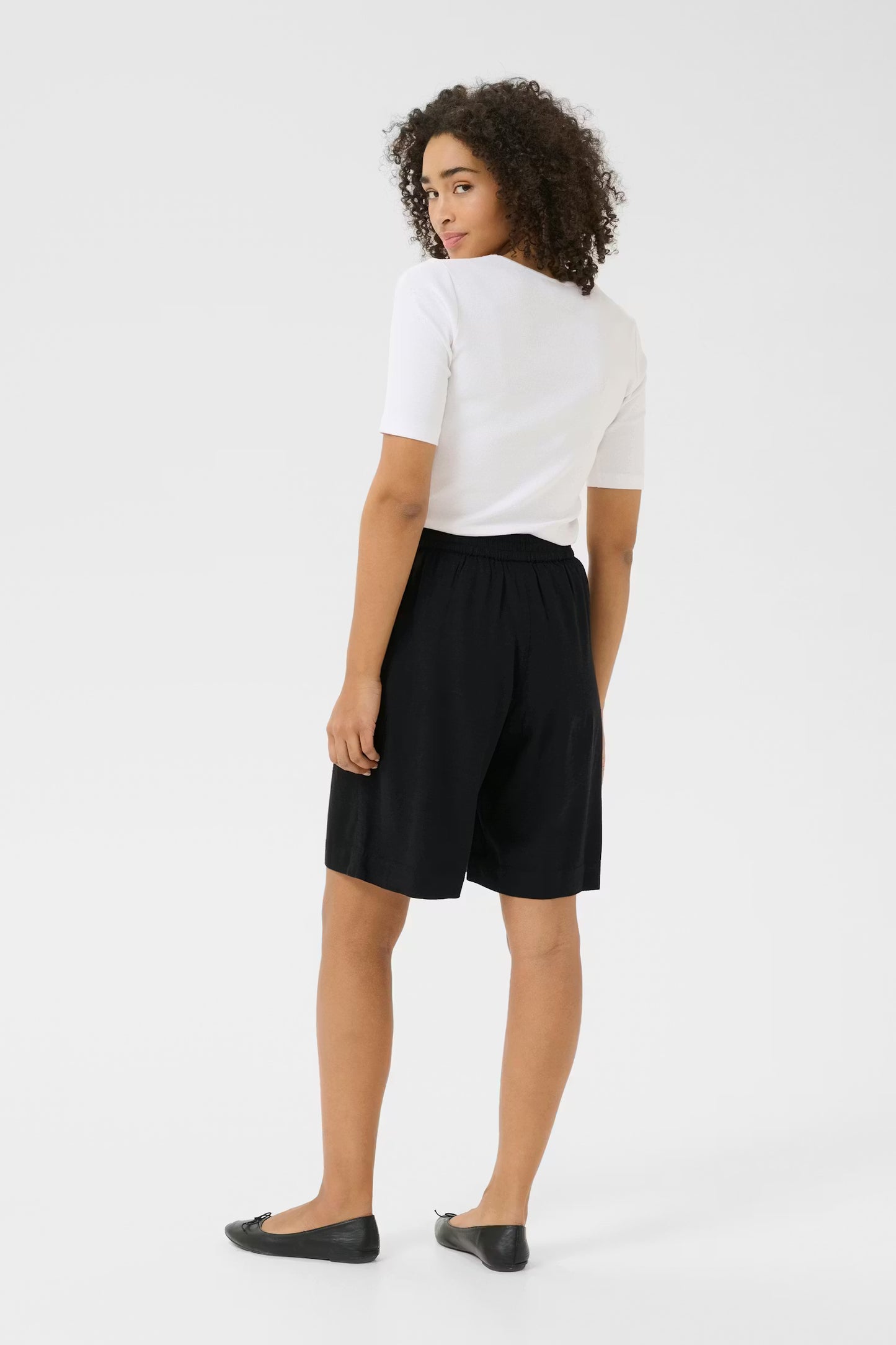 Person wearing a white t-shirt and black shorts on a white background
