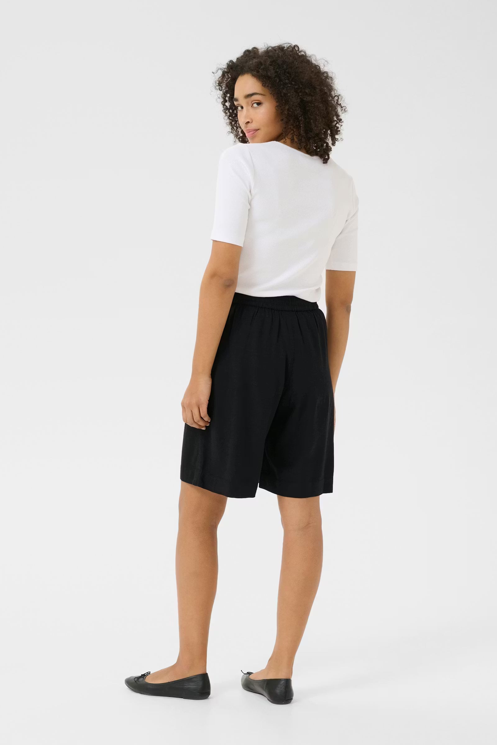 Person wearing a white t-shirt and black shorts on a white background