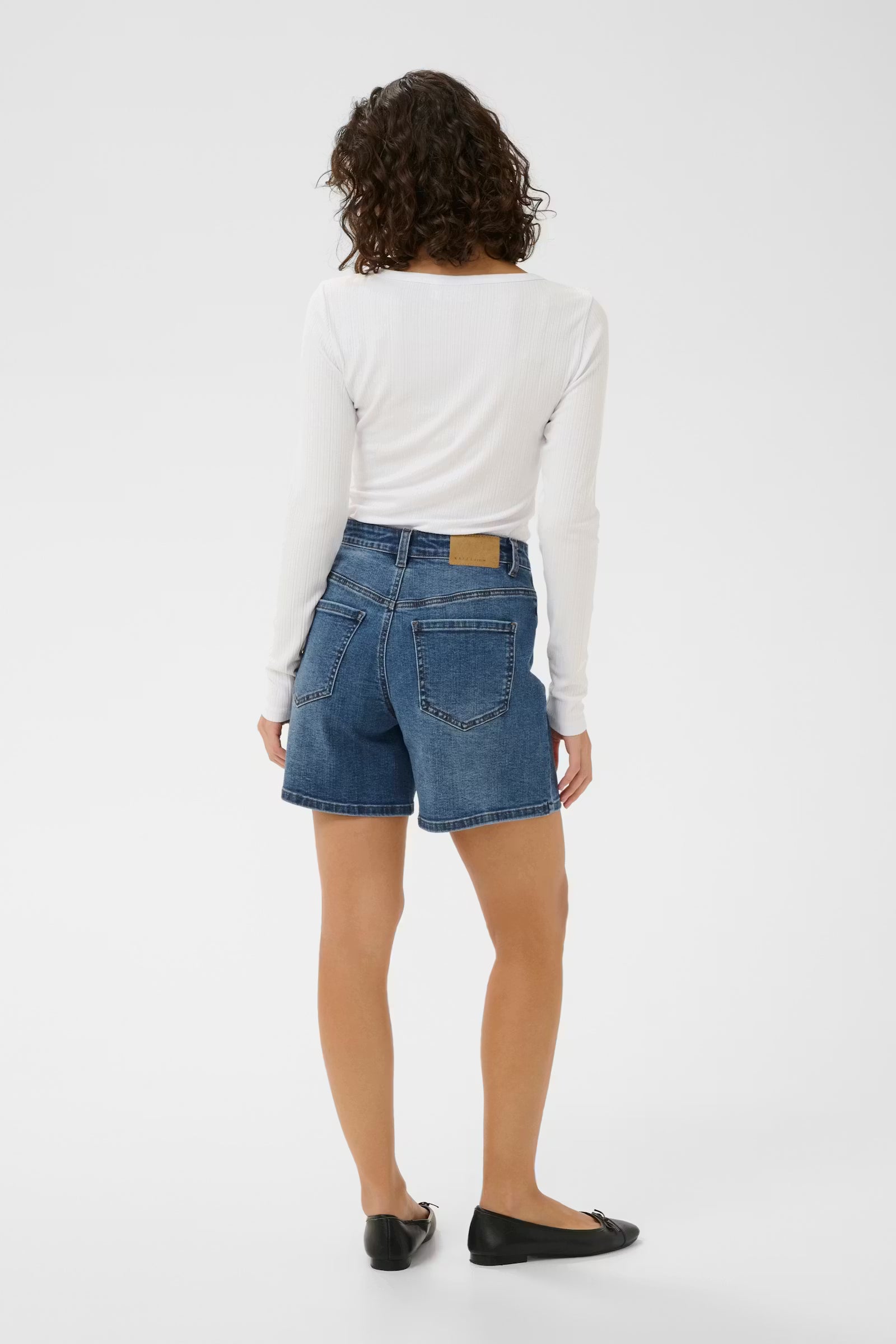 Person wearing blue denim shorts and a white long-sleeve shirt on a white background