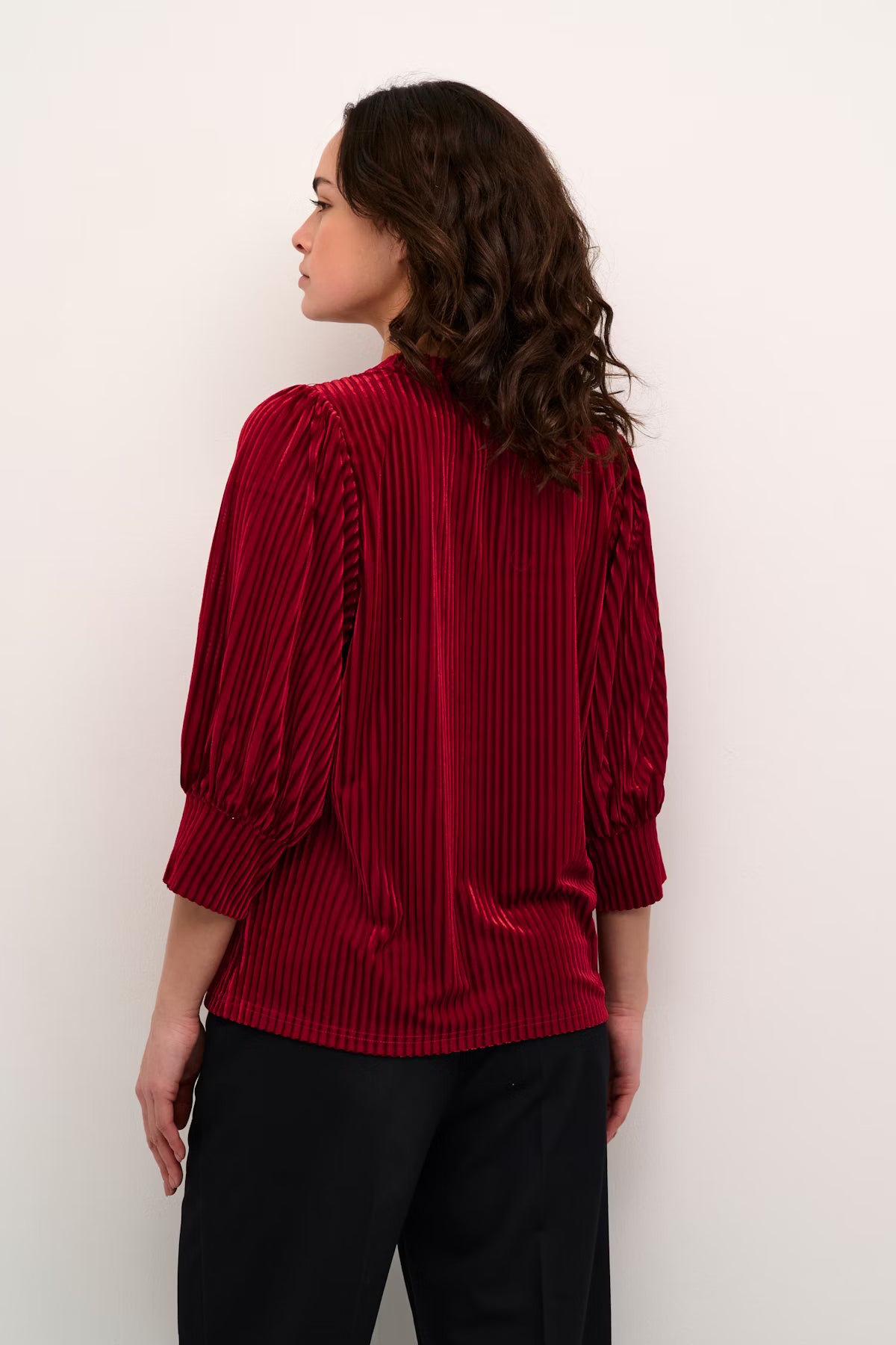 Woman wearing a red pleated blouse against a white background