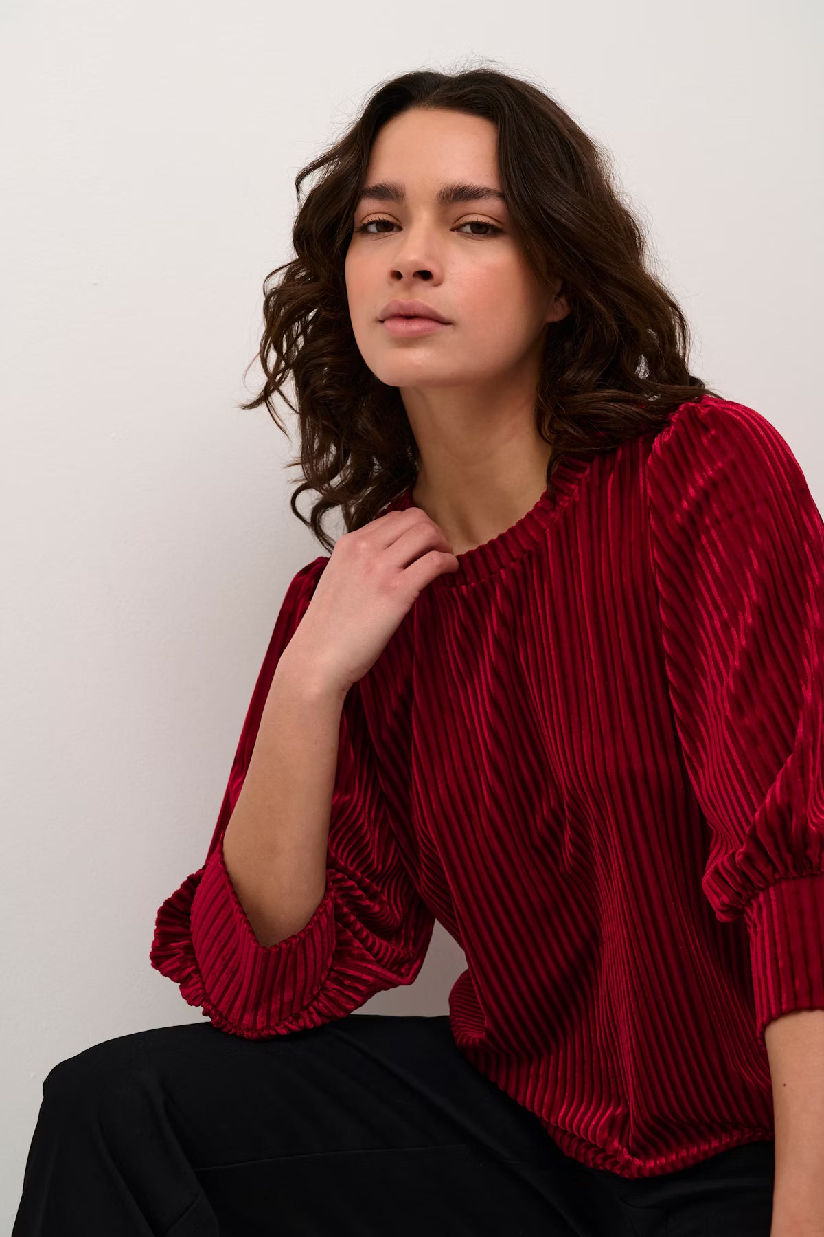 Woman wearing a red textured blouse against a white background