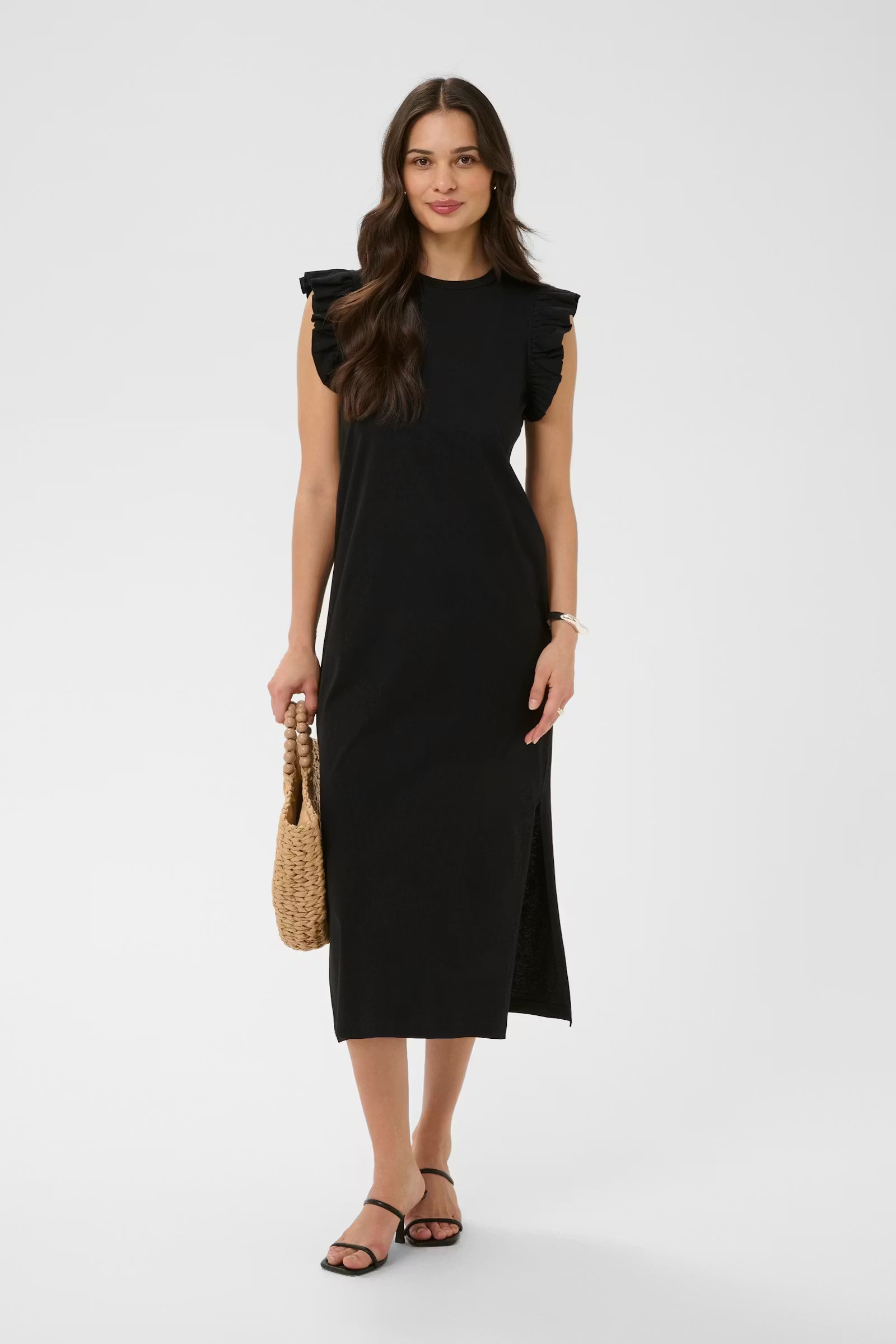 Woman wearing a black dress holding a woven handbag on a white background