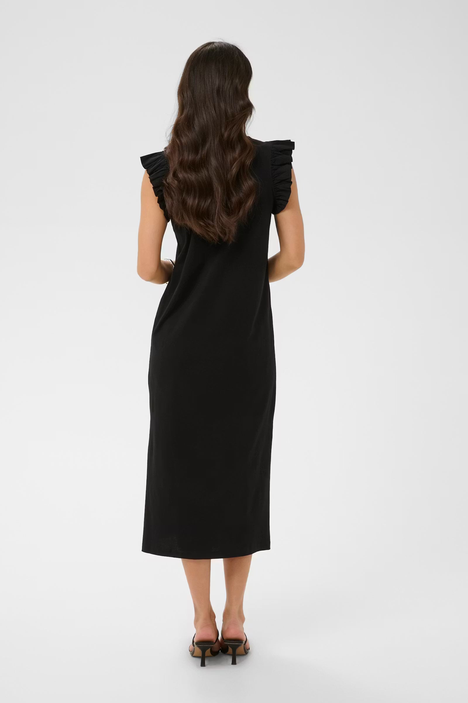 Woman wearing a black dress with ruffled shoulders on a white background