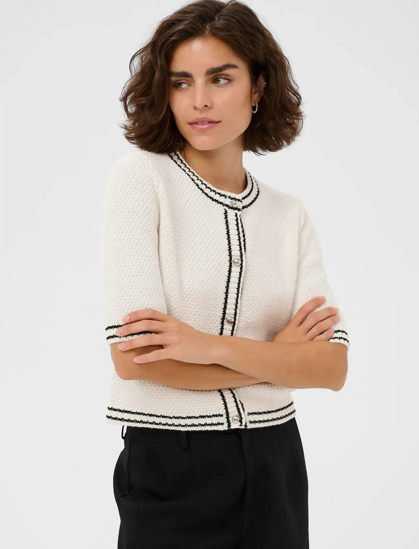 Woman wearing a white and black patterned jacket on a plain background