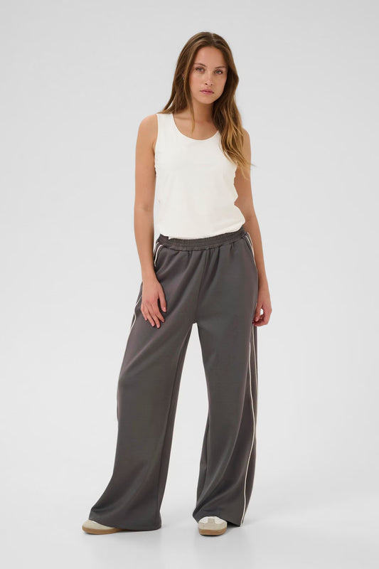 Woman wearing a white sleeveless top and gray wide-leg pants on a white background