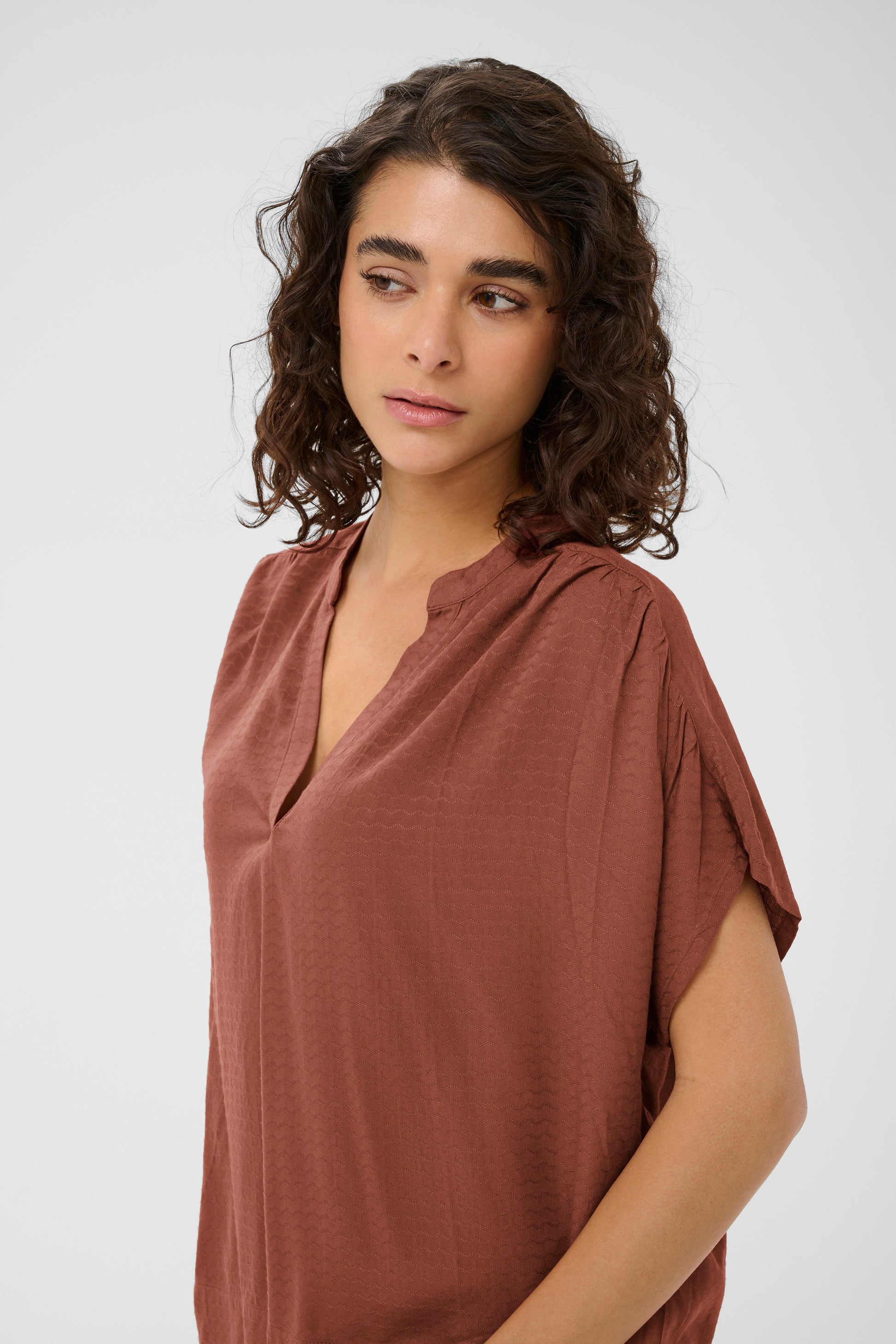 Woman wearing a brown top against a white background