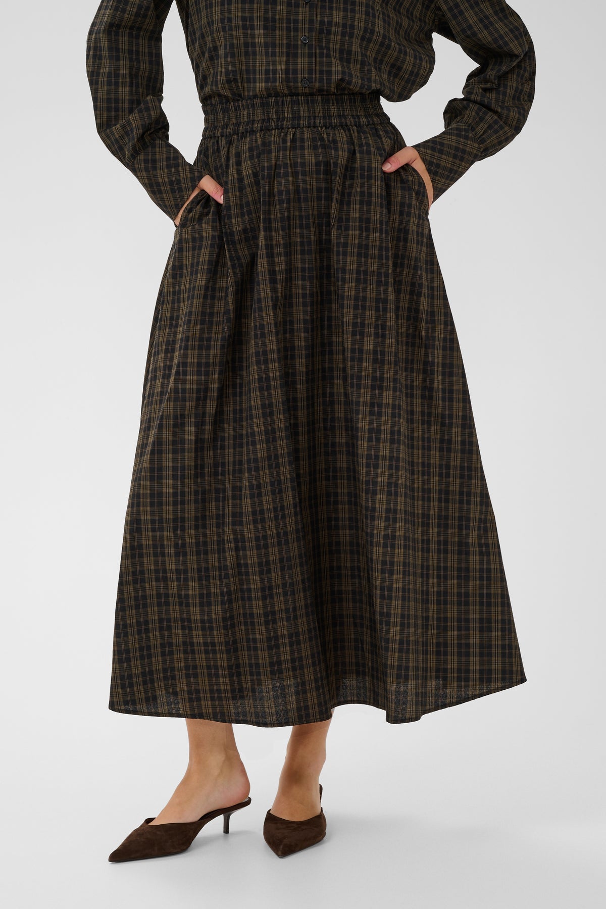 Person wearing a plaid dress with long sleeves on a white background