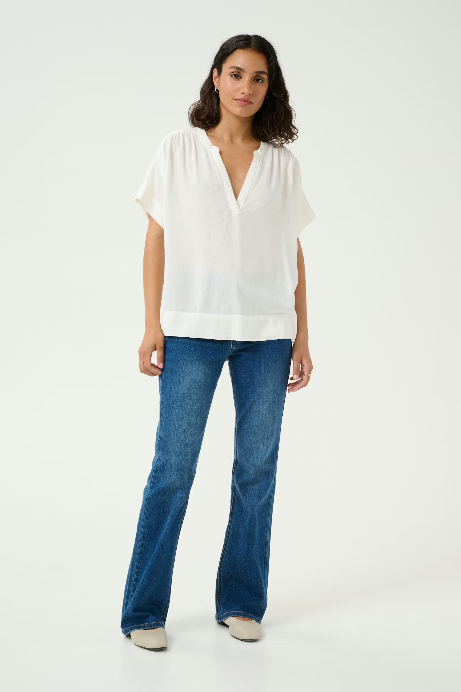Woman wearing a white blouse and blue jeans on a white background