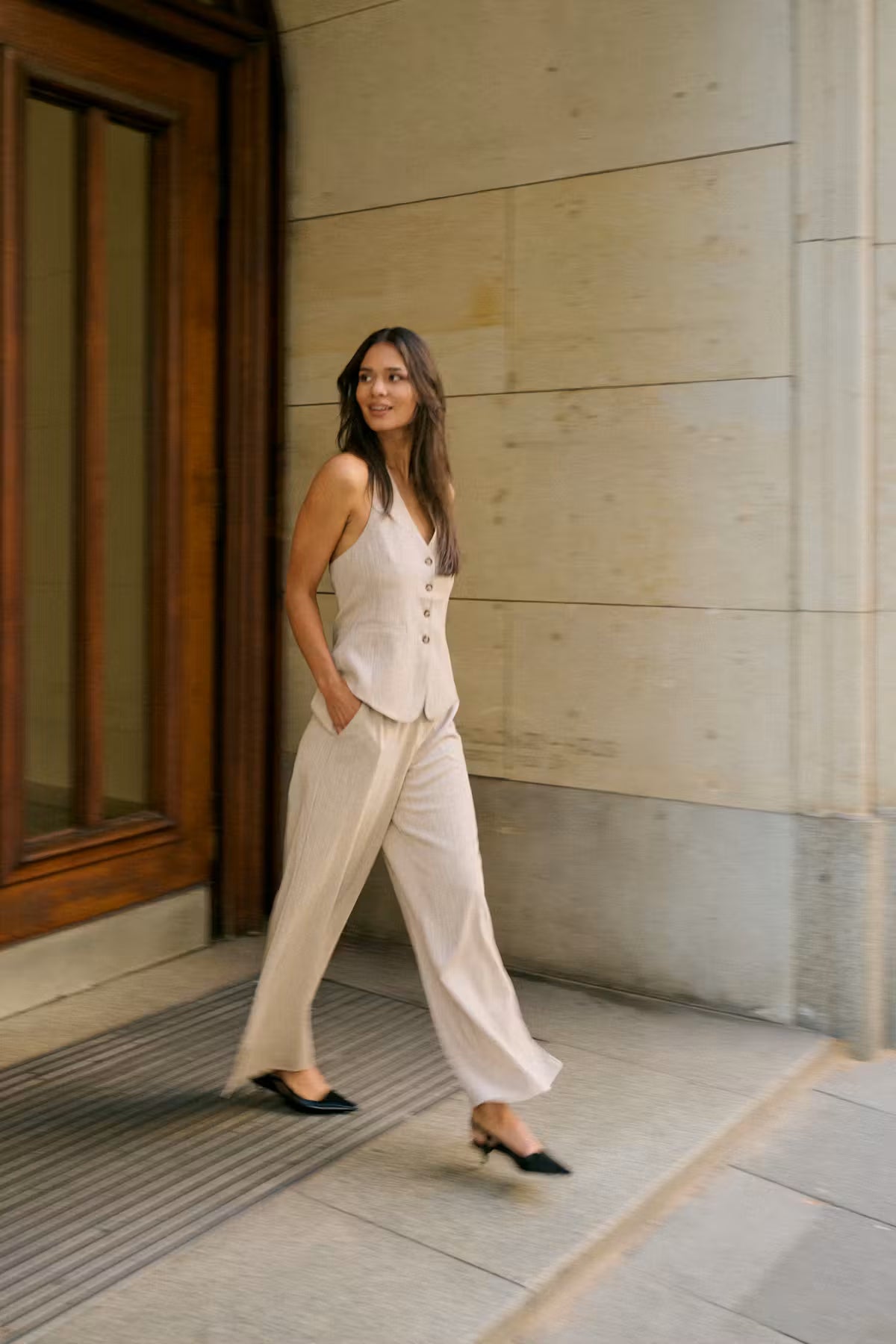Woman in a beige suit standing outside a building