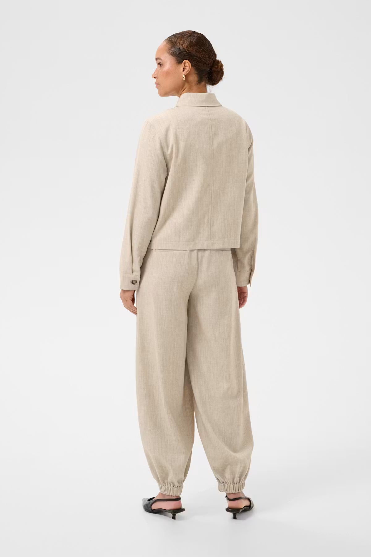 woman wearing a beige outfit on a white background