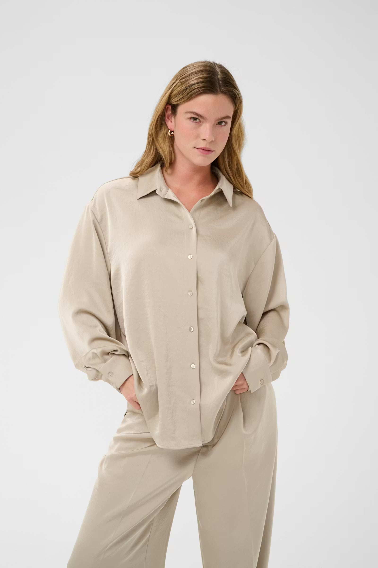 Woman wearing a beige shirt and pants on a white background