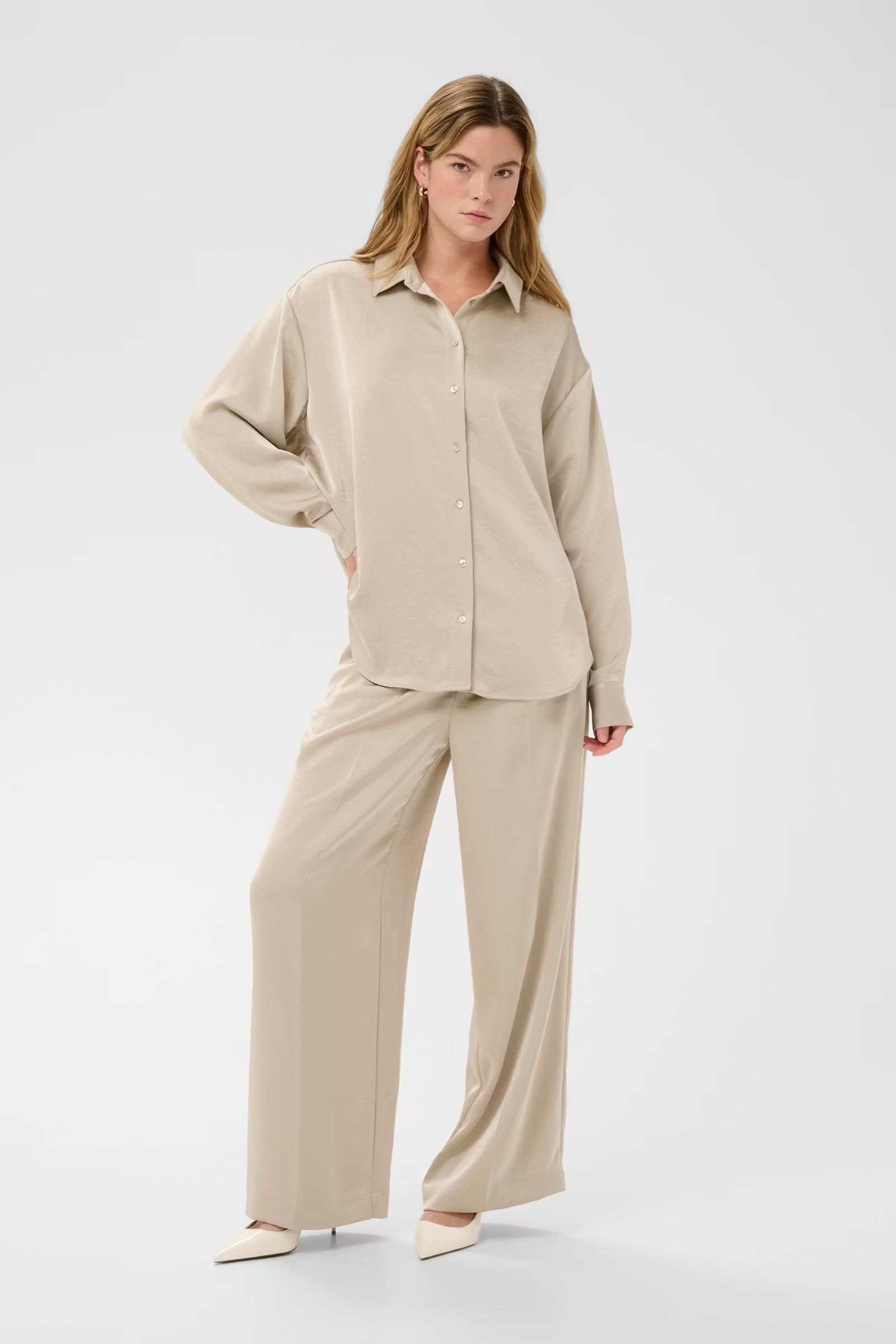 Woman wearing a beige shirt and pants set on a white background