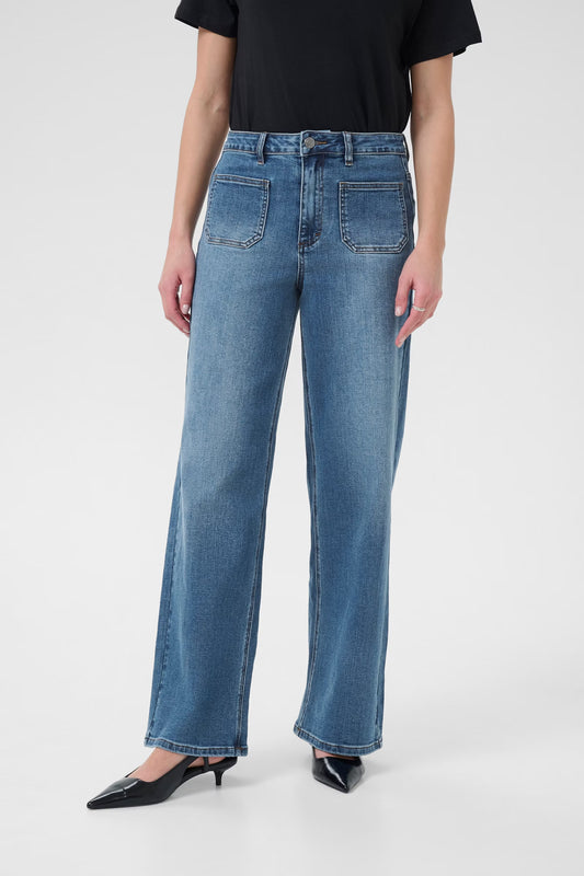 Person wearing blue jeans and a black top on a white background