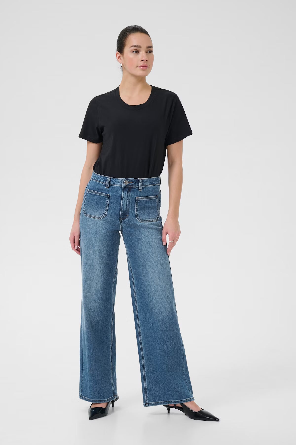 Woman wearing a black t-shirt and blue jeans on a white background