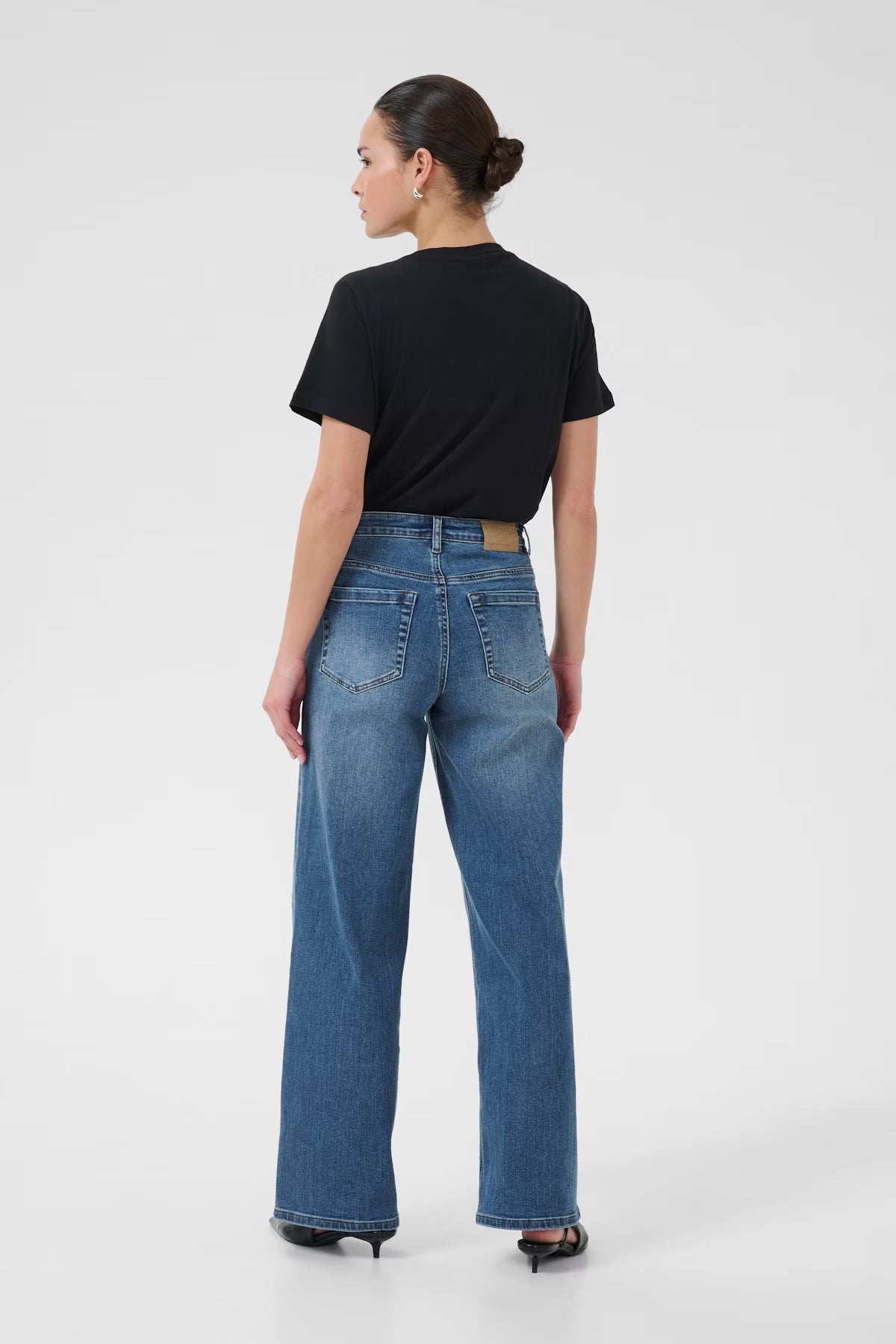 Person wearing blue jeans and a black shirt on a white background
