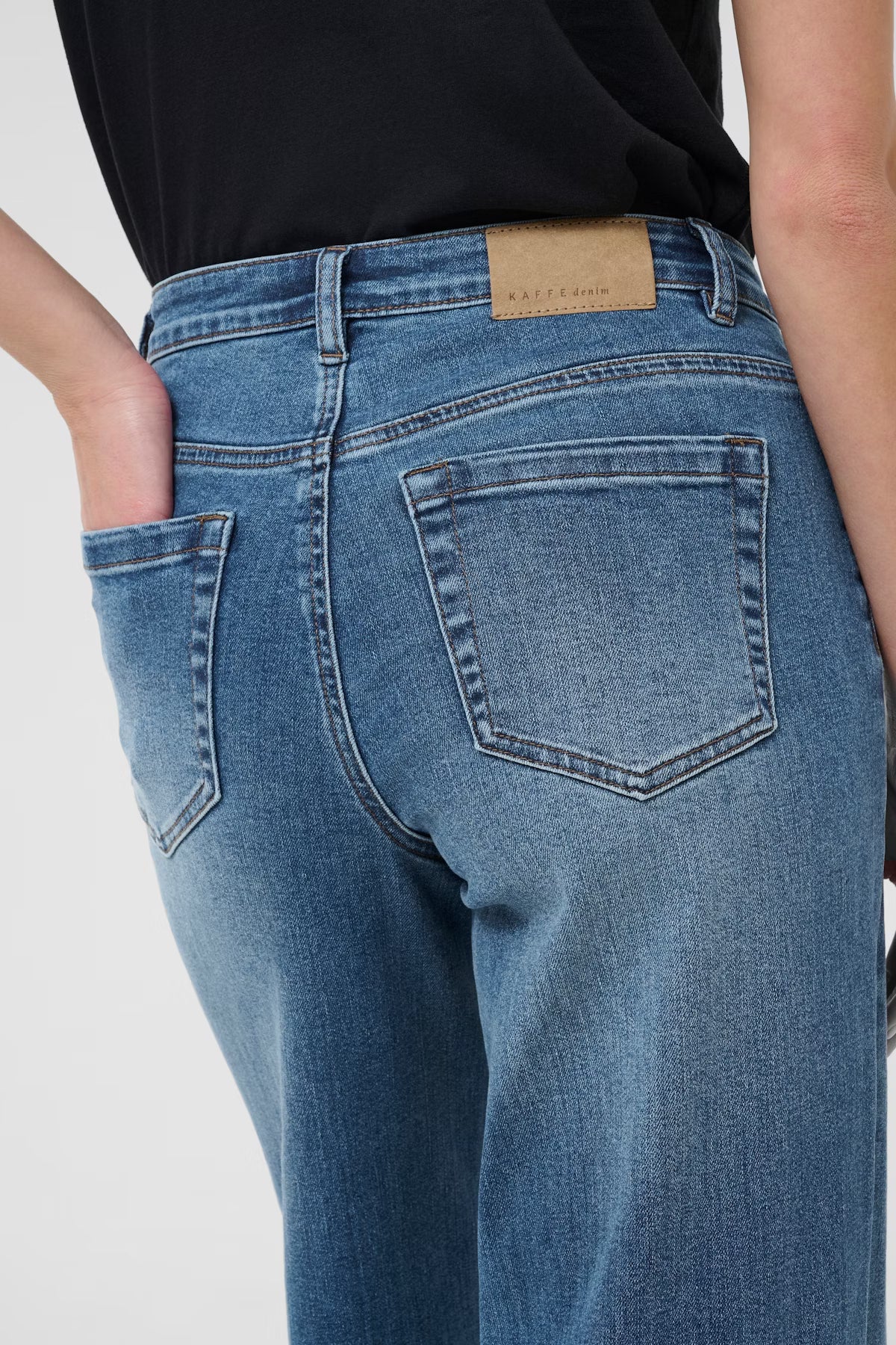 Blue jeans with a brand label on a plain background