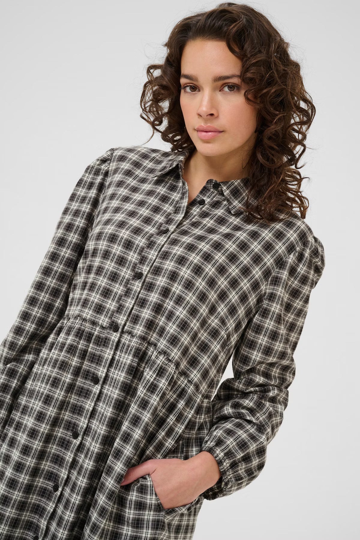 Woman wearing a plaid shirt dress against a white background