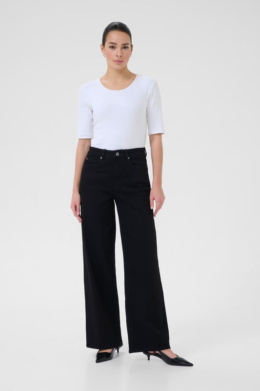 Woman wearing a white top and black wide-leg jeans on a white background