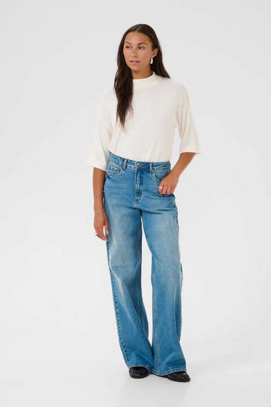 Woman wearing a white sweater and blue jeans on a white background