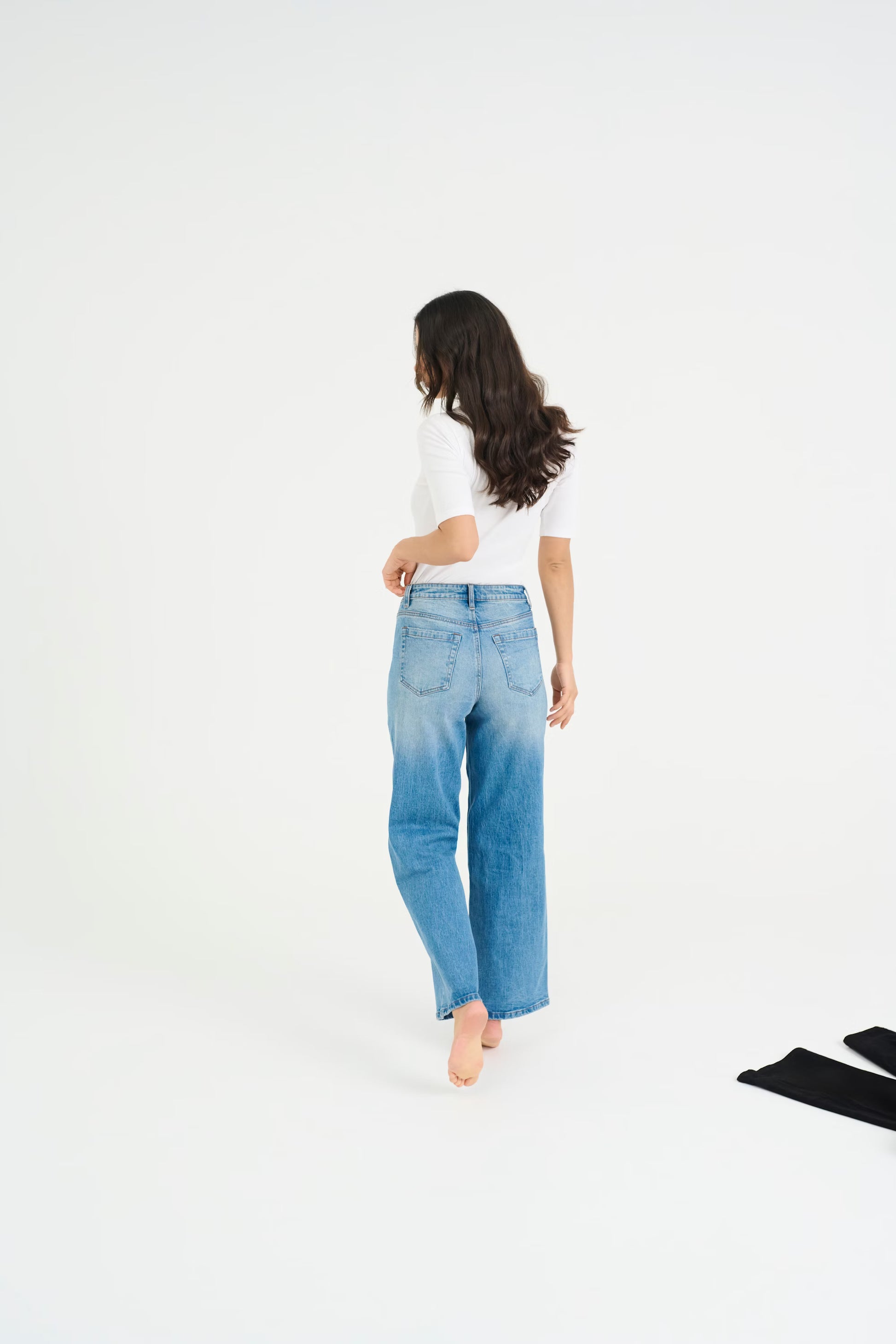 Woman wearing blue jeans and a white shirt on a white background