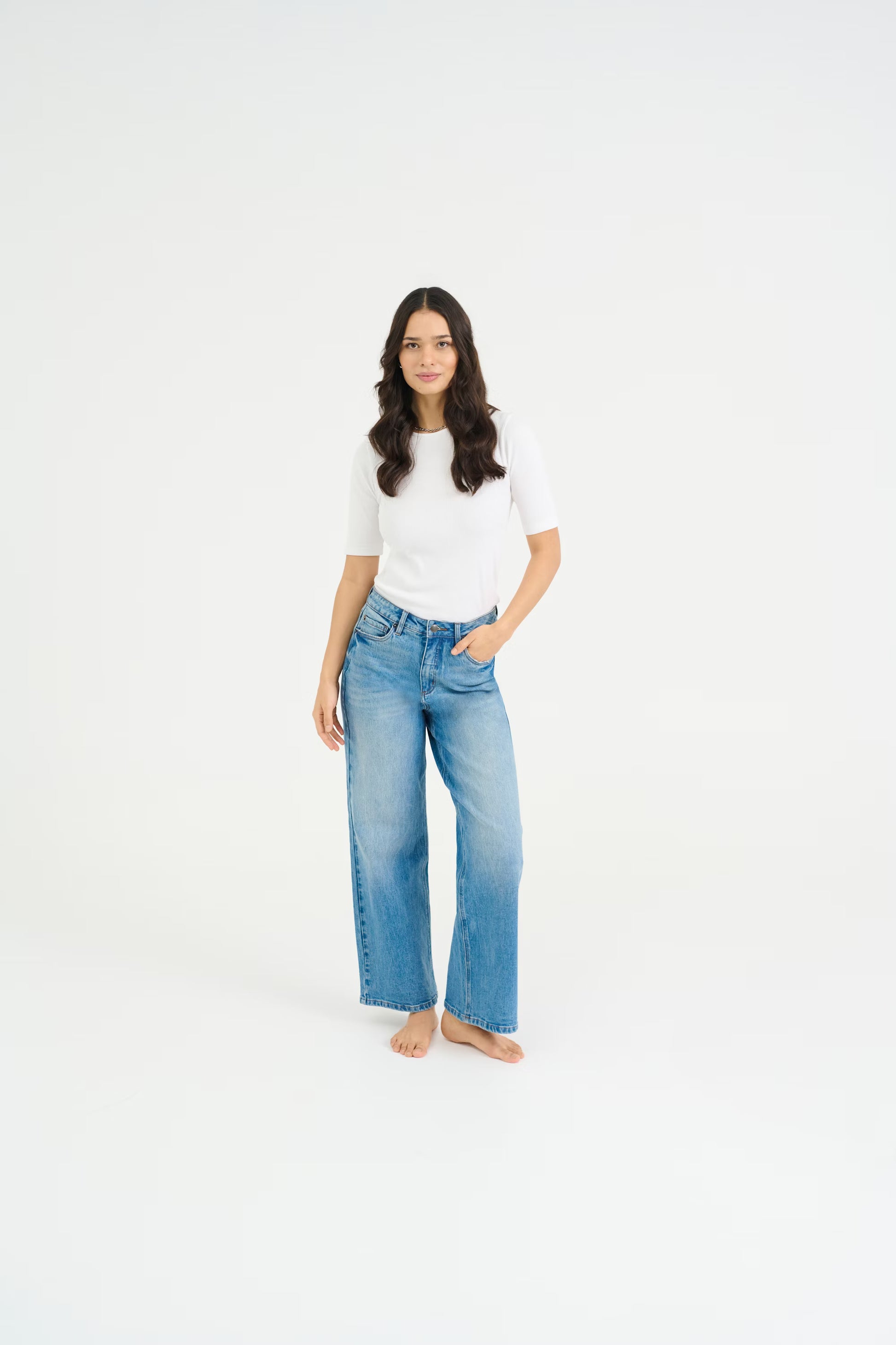 Woman wearing a white shirt and blue jeans on a white background