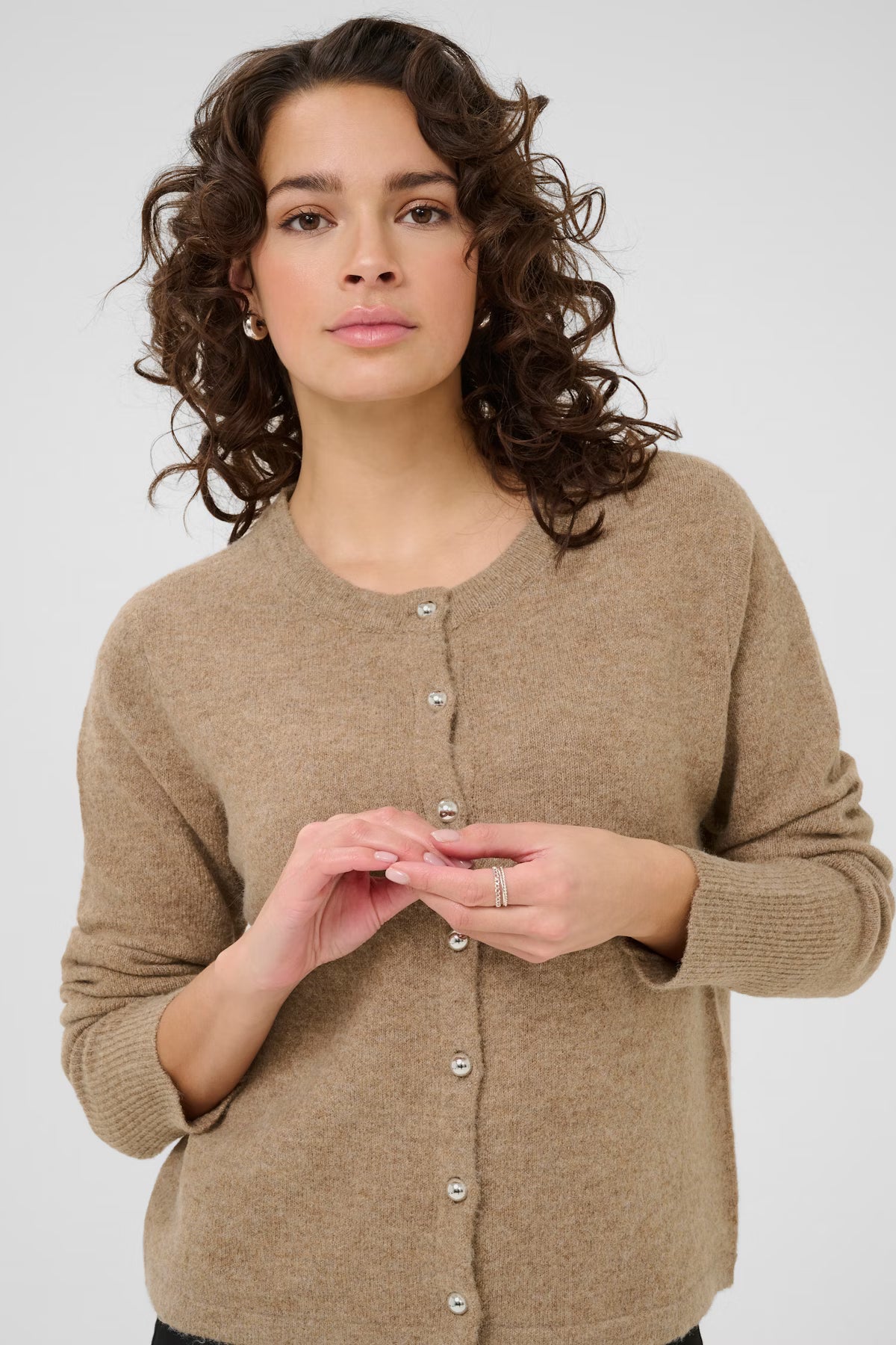 Woman wearing a beige cardigan against a white background